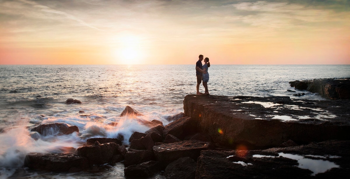 wedding photography hobart, tasmania by svenstudios 11 Couple embracing on a rocky shoreline at sunset beside the ocean in Hobart, Tasmania
