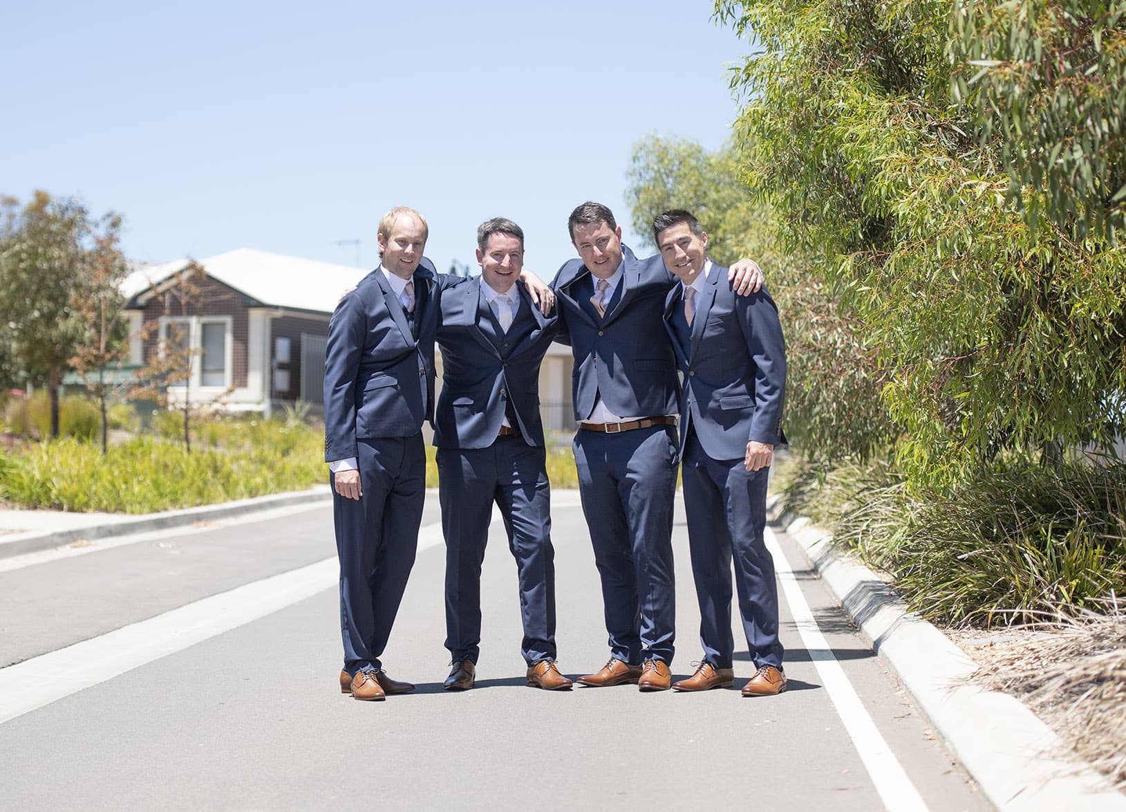 serafino wines wedding - claire & arron 16 groomsmen huddle on road