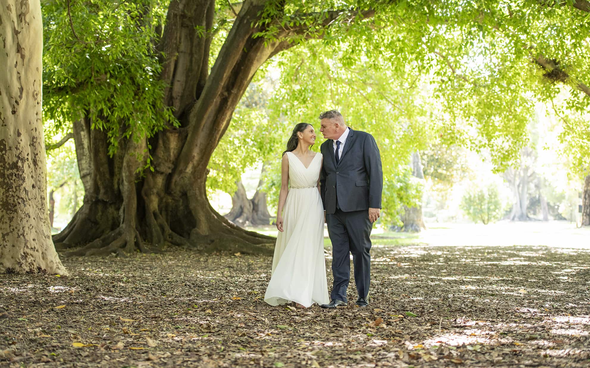 botanic park wedding - naz & peter 26 Bride and groom walking under the trees after their Botanic Park Wedding Ceremony