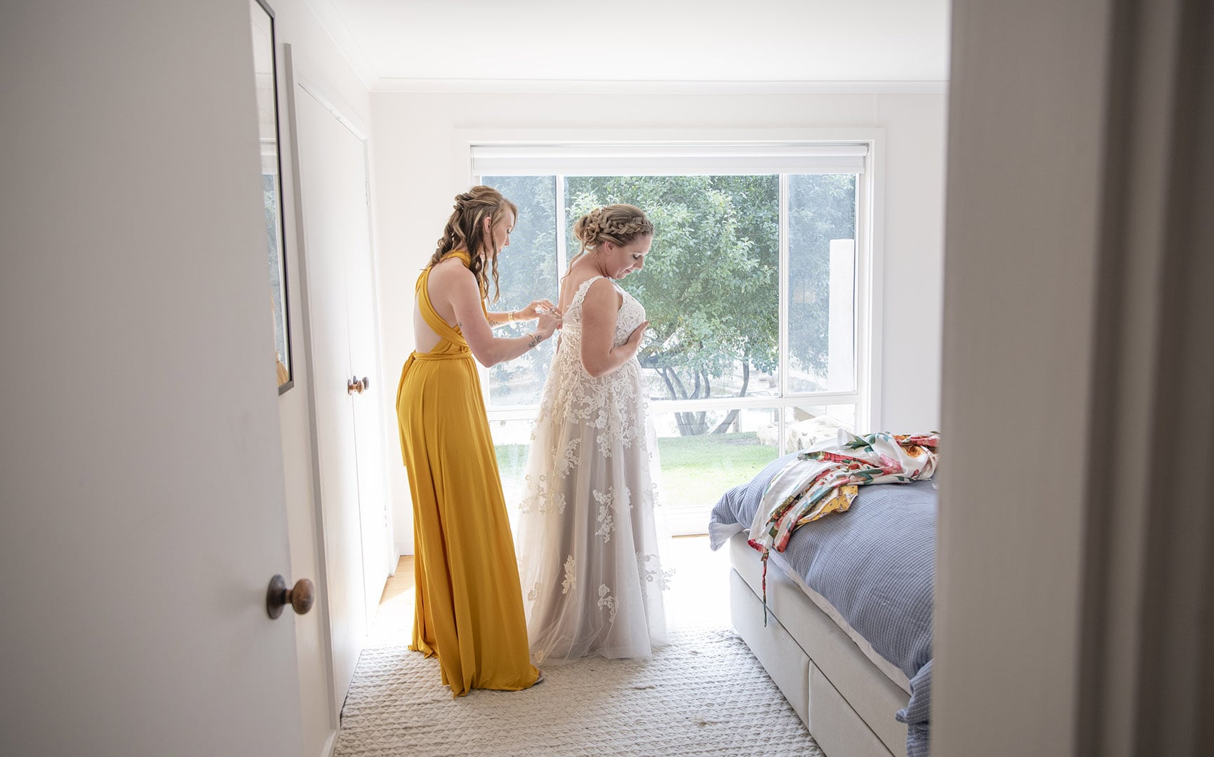 old oval estate wedding - suzie & jay 70 Bridesmaid helping put dress on through doorframe