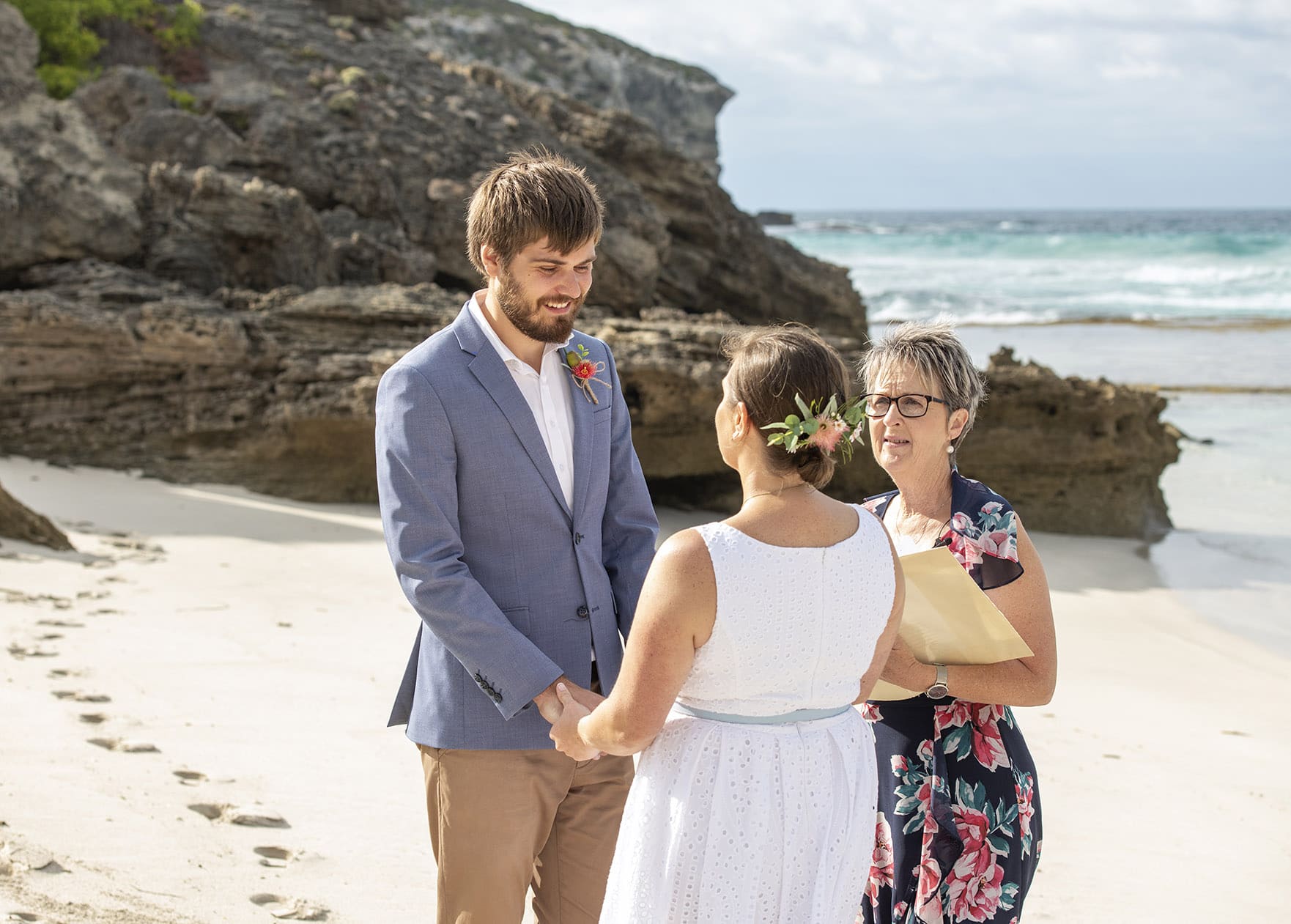 kangaroo island elopement - claire & jacob 25 Claire and Jacob holding hands with their celebrant during their beach elopement ceremony beside rocky cliffs on Kangaroo Island