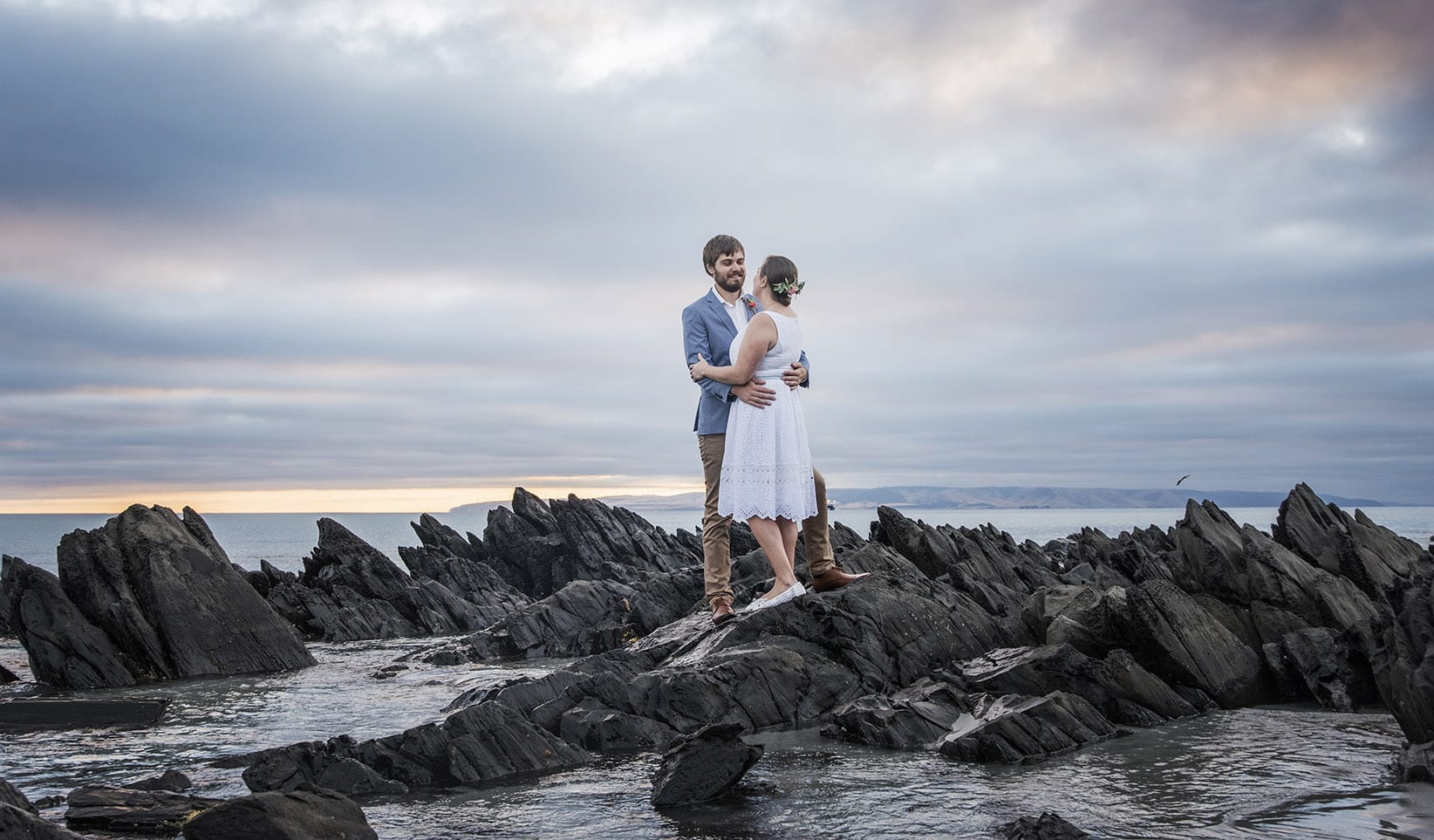 kangaroo island elopement - claire & jacob 5 Claire and Jacob embracing on dark coastal rocks at Frenchman's Rock, Kangaroo Island