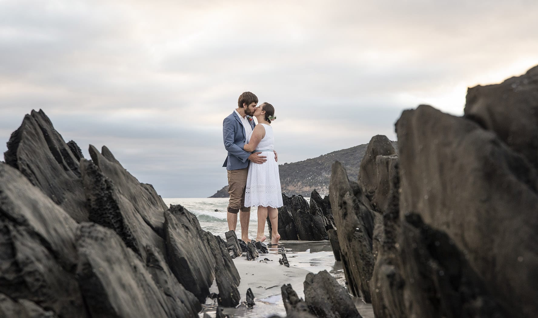 kangaroo island elopement - claire & jacob 8 Claire and Jacob kissing among dark rock formations on Penneshaw beach during their Kangaroo Island elopement