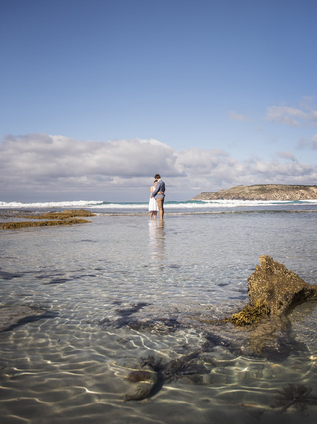 kangaroo island elopement - claire & jacob 36 Claire and Jacob embracing in shallow water at Pennington Bay, Kangaroo Island, with waves and a rocky headland behind them