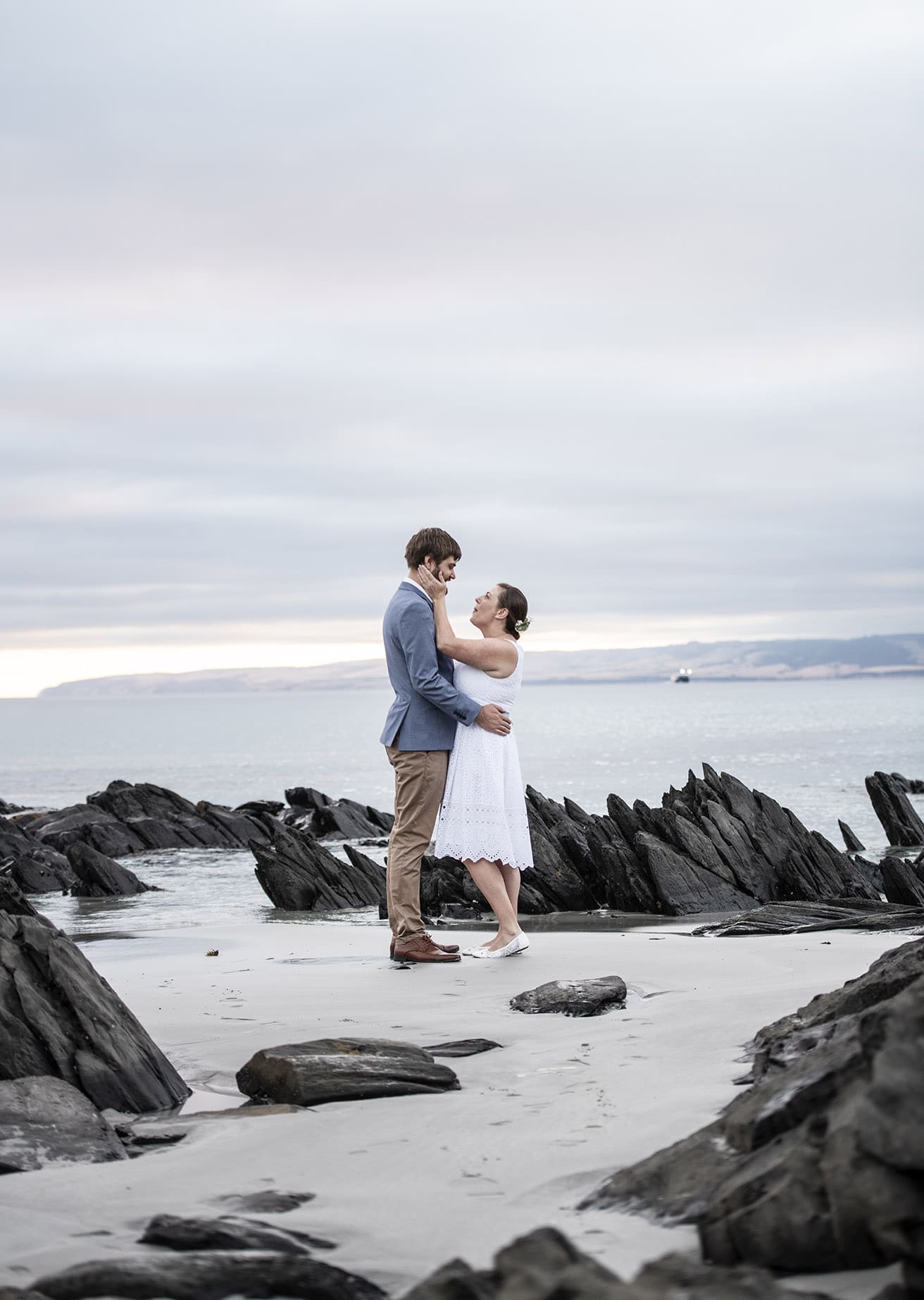 kangaroo island elopement - claire & jacob 2 Claire and Jacob embracing on the sandy, rock-lined shore at Frenchman's Rock, Kangaroo Island