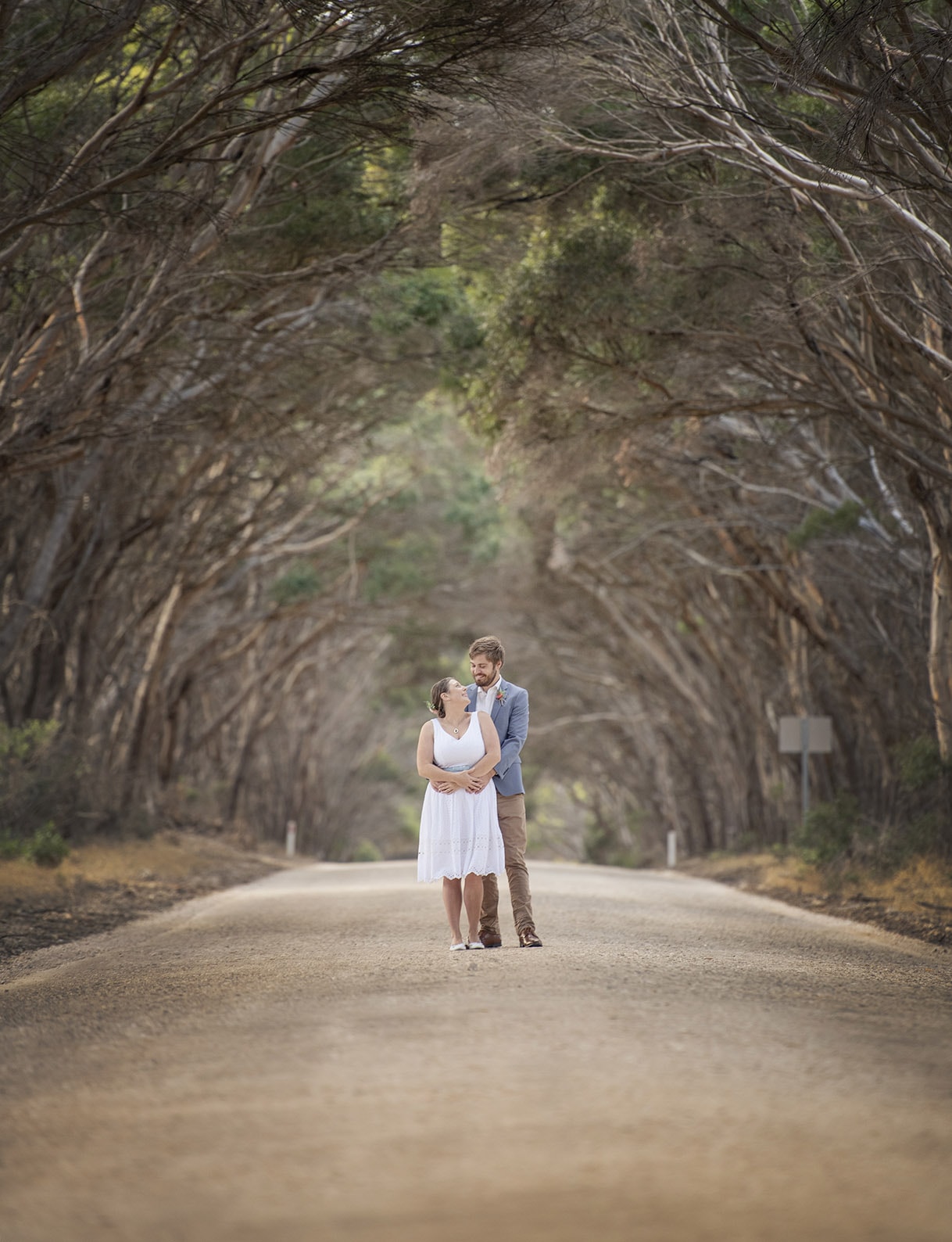 kangaroo island elopement - claire & jacob 15 Claire and Jacob embracing on a quiet tree-lined road during their Kangaroo Island elopement