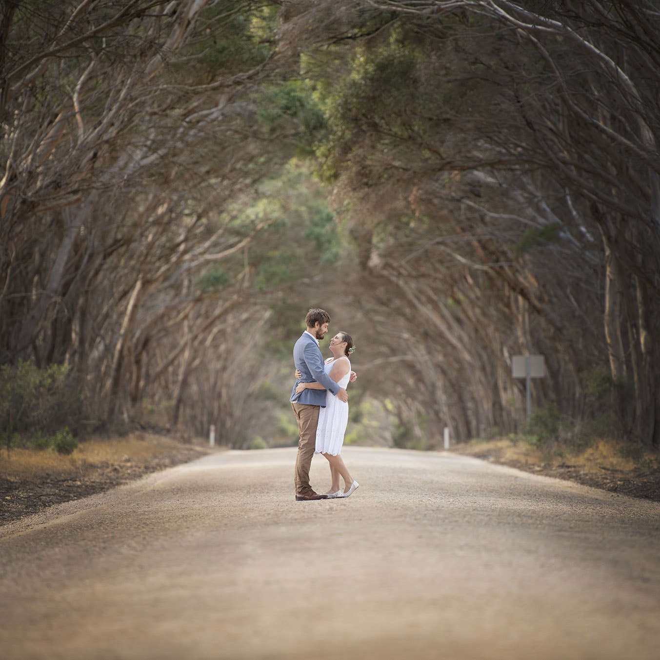 kangaroo island elopement - claire & jacob 14 Claire and Jacob embracing on a quiet road beneath arching trees during their Kangaroo Island elopement
