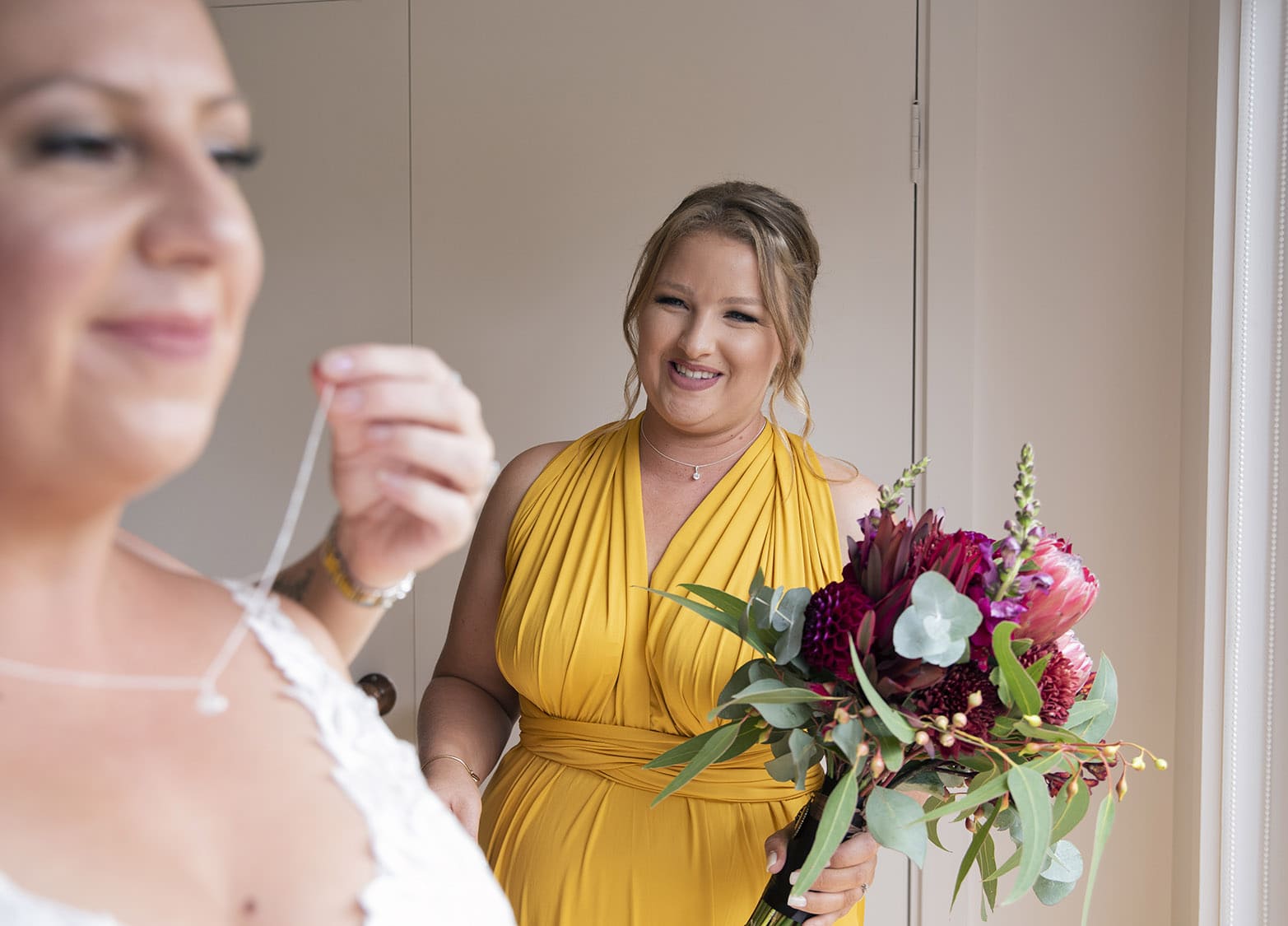 old oval estate wedding - suzie & jay 72 Smiling bridesmaid looking on at bride getting ready