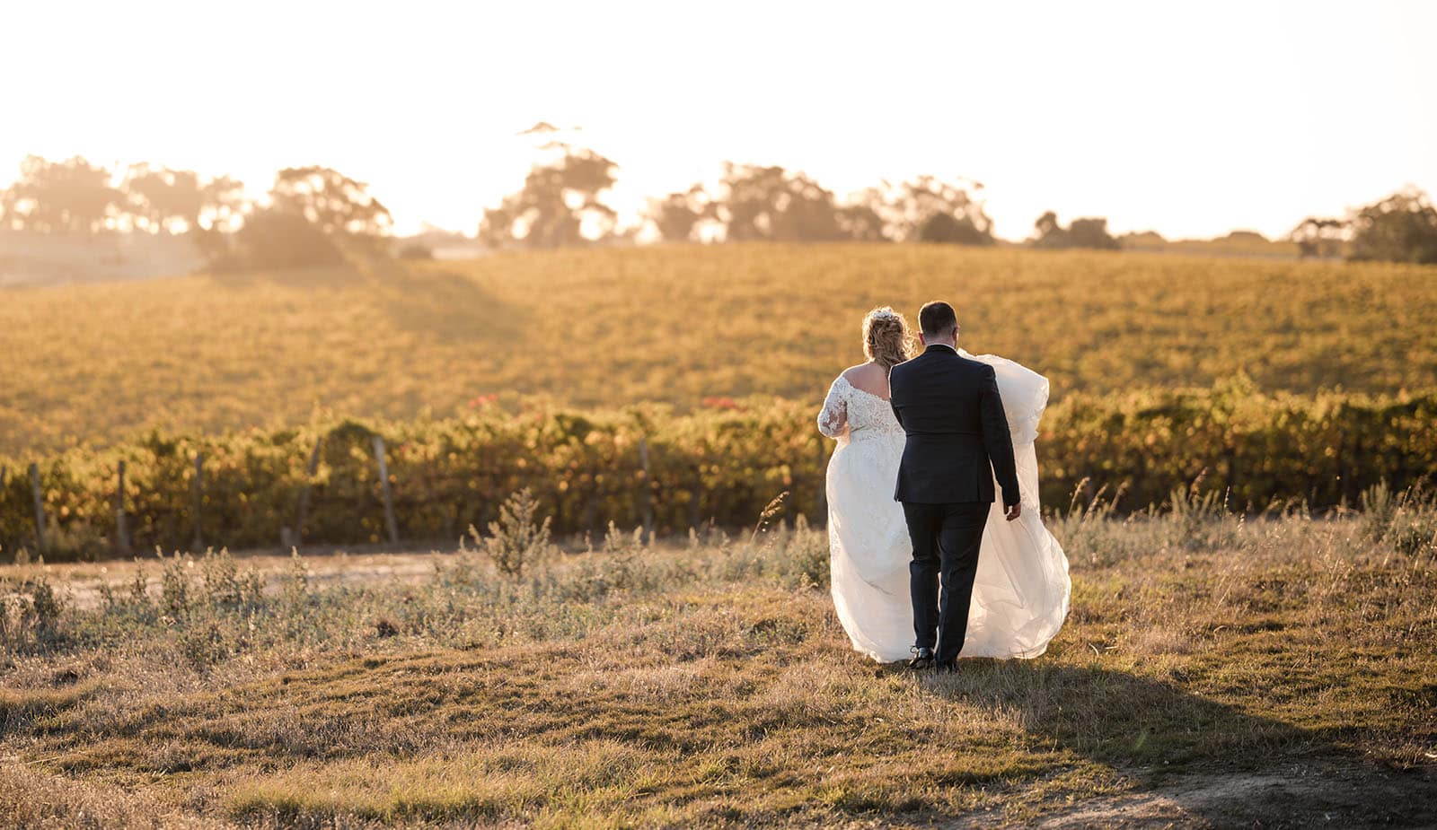 mclaren vale ekhidna wines wedding - kait & brayden 47 Bride and groom walking towards sunset and vines