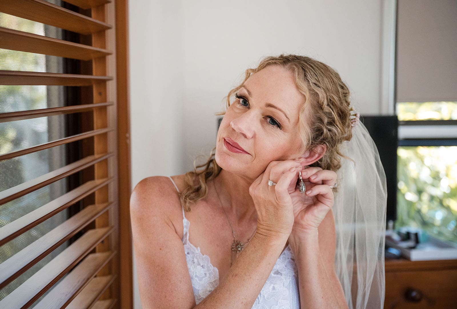 darwin's dudley point wedding - melanie & kerry 17 bride putting on ear rings nearby window