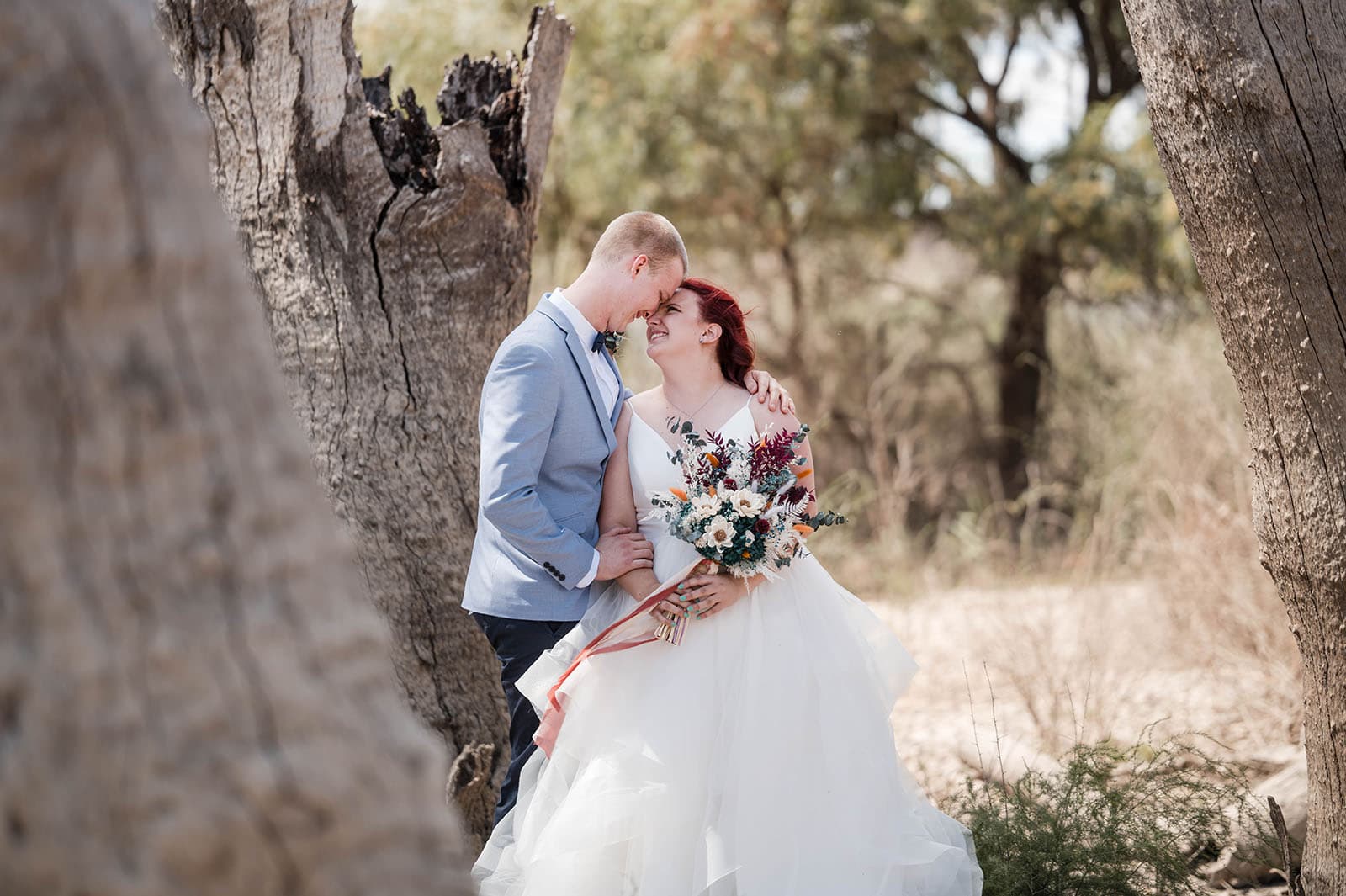 riverland wine centre wedding - lisa & mitch 184 Bride and groom getting close between tree stumps