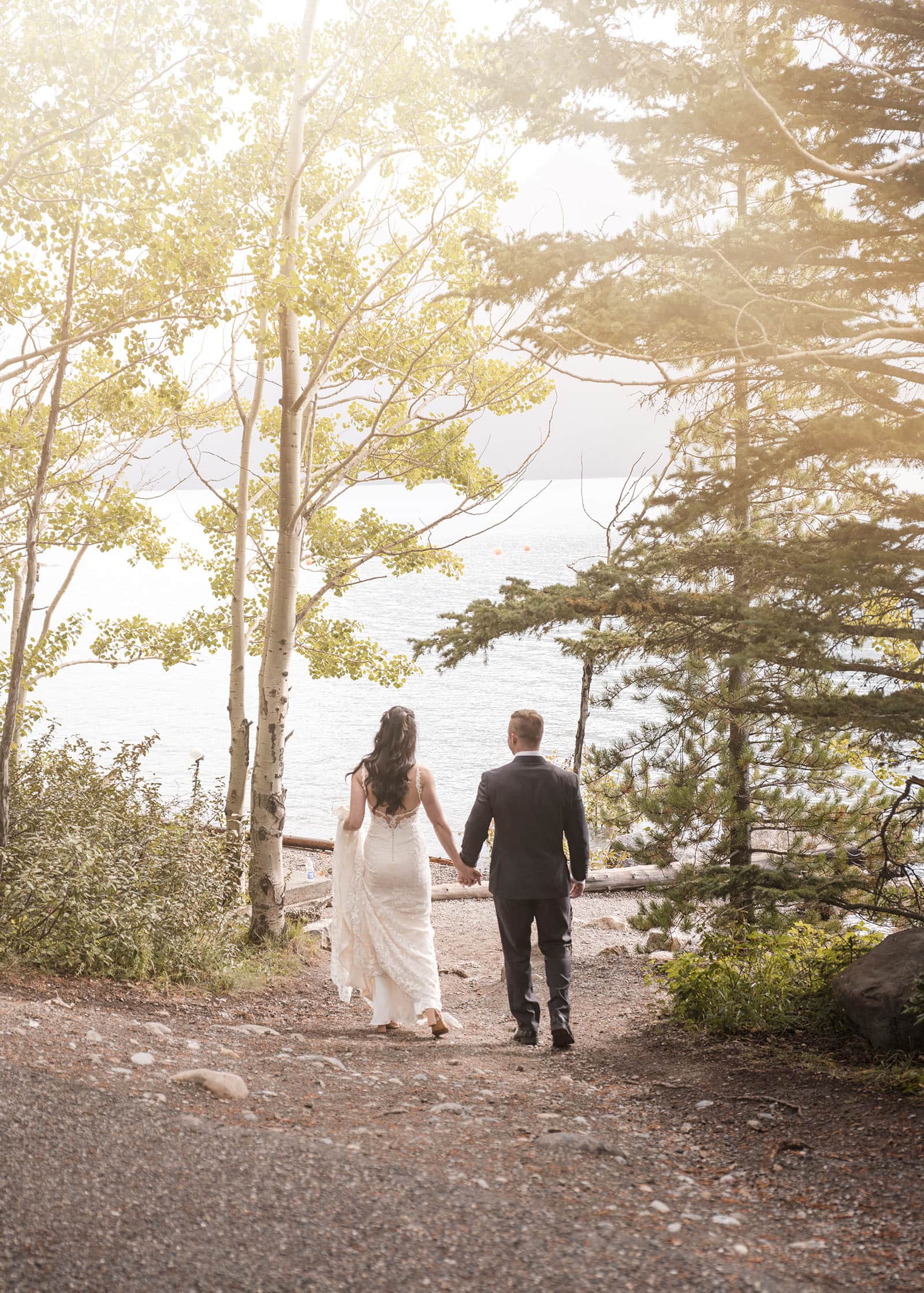 canada's lake louise wedding photoshoot - melodie & brandon 11 Bridal couple walking to Lake Minnewanka