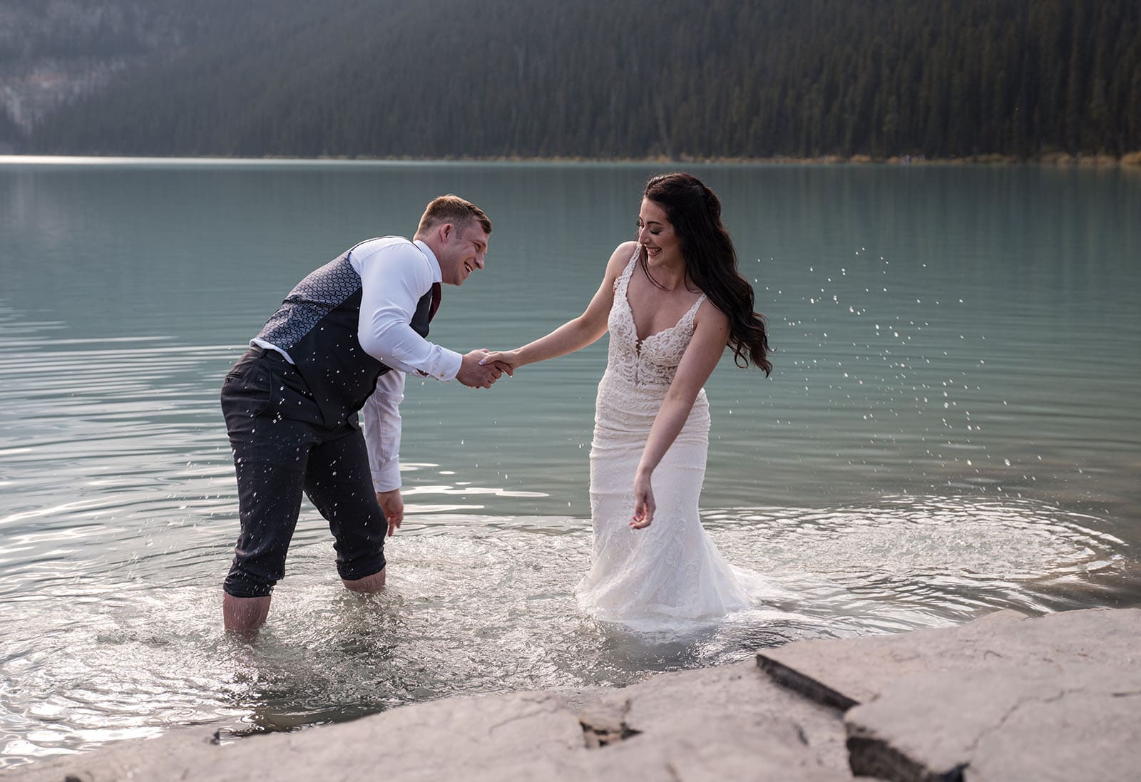 canada's lake louise wedding photoshoot - melodie & brandon 19 Bride and groom splashing one another in Lake Louise