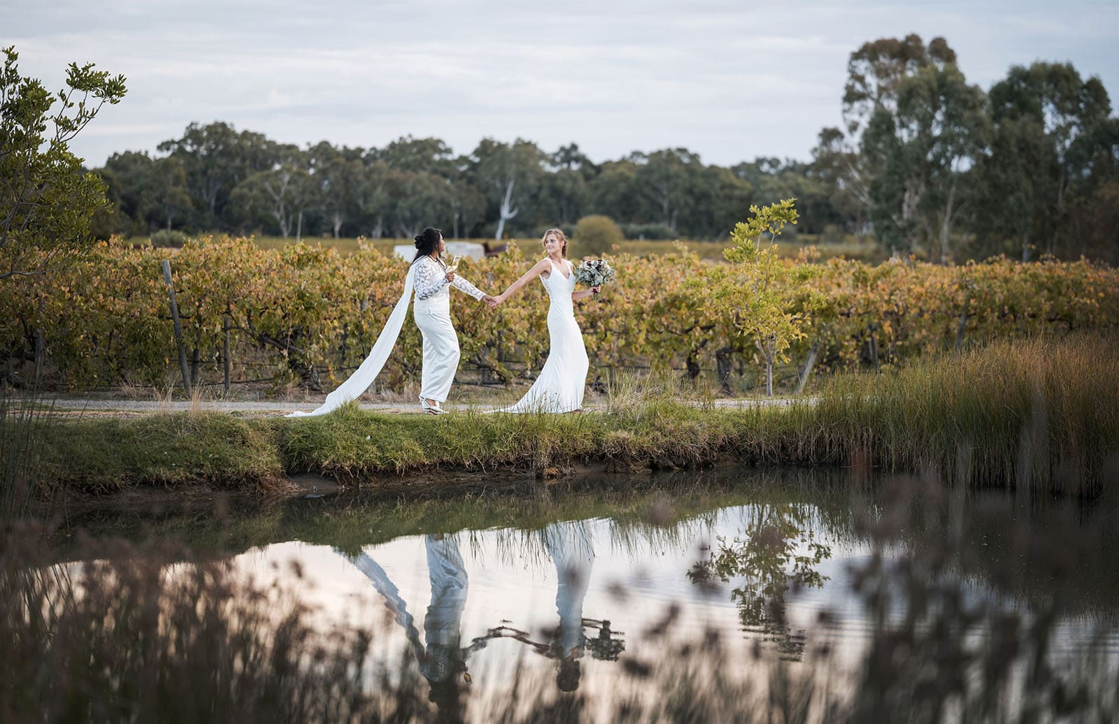 vine shed wedding - kat & katie 241 brides walking along pond edge