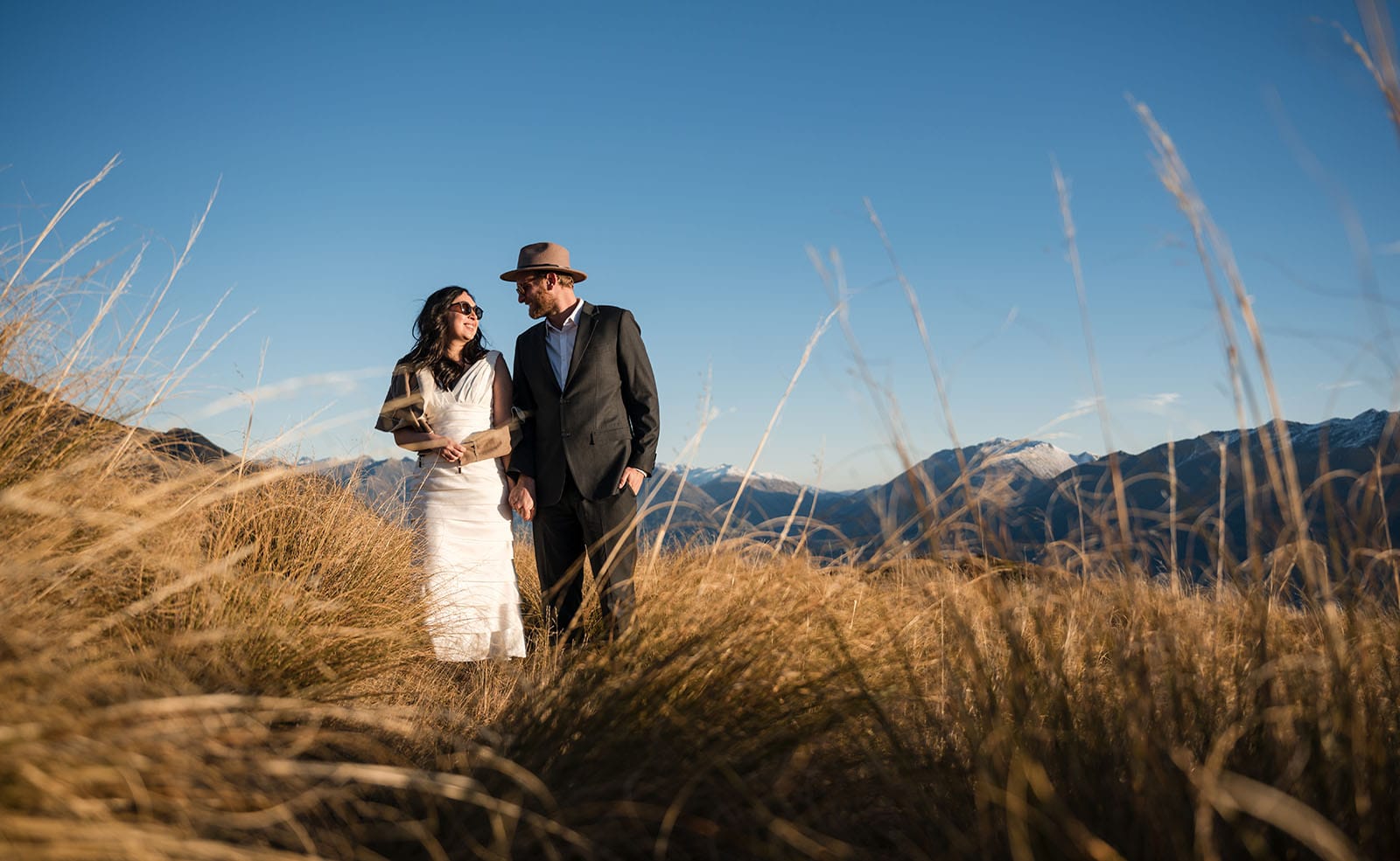 incredible queenstown wedding photoshoot - wendy & frank 44 Bride and groom in long grass on mountain