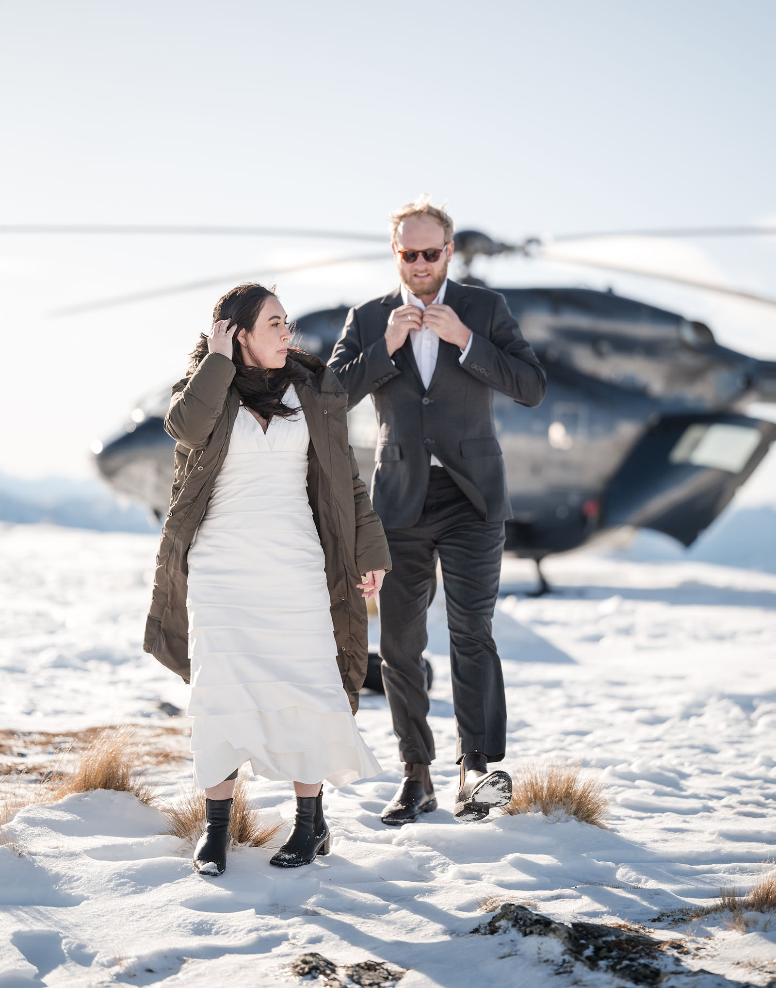 incredible queenstown wedding photoshoot - wendy & frank 23 Bride and groom walking from helicopter