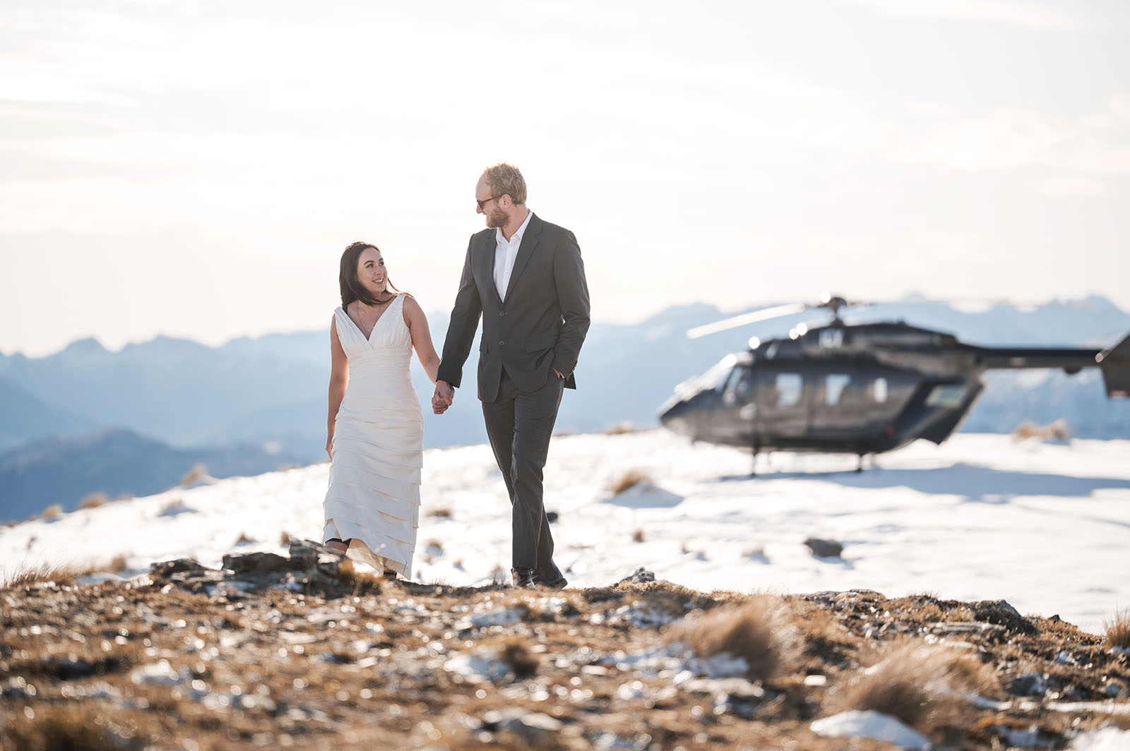 incredible queenstown wedding photoshoot - wendy & frank 24 Bride and groom walking in front of helicopter