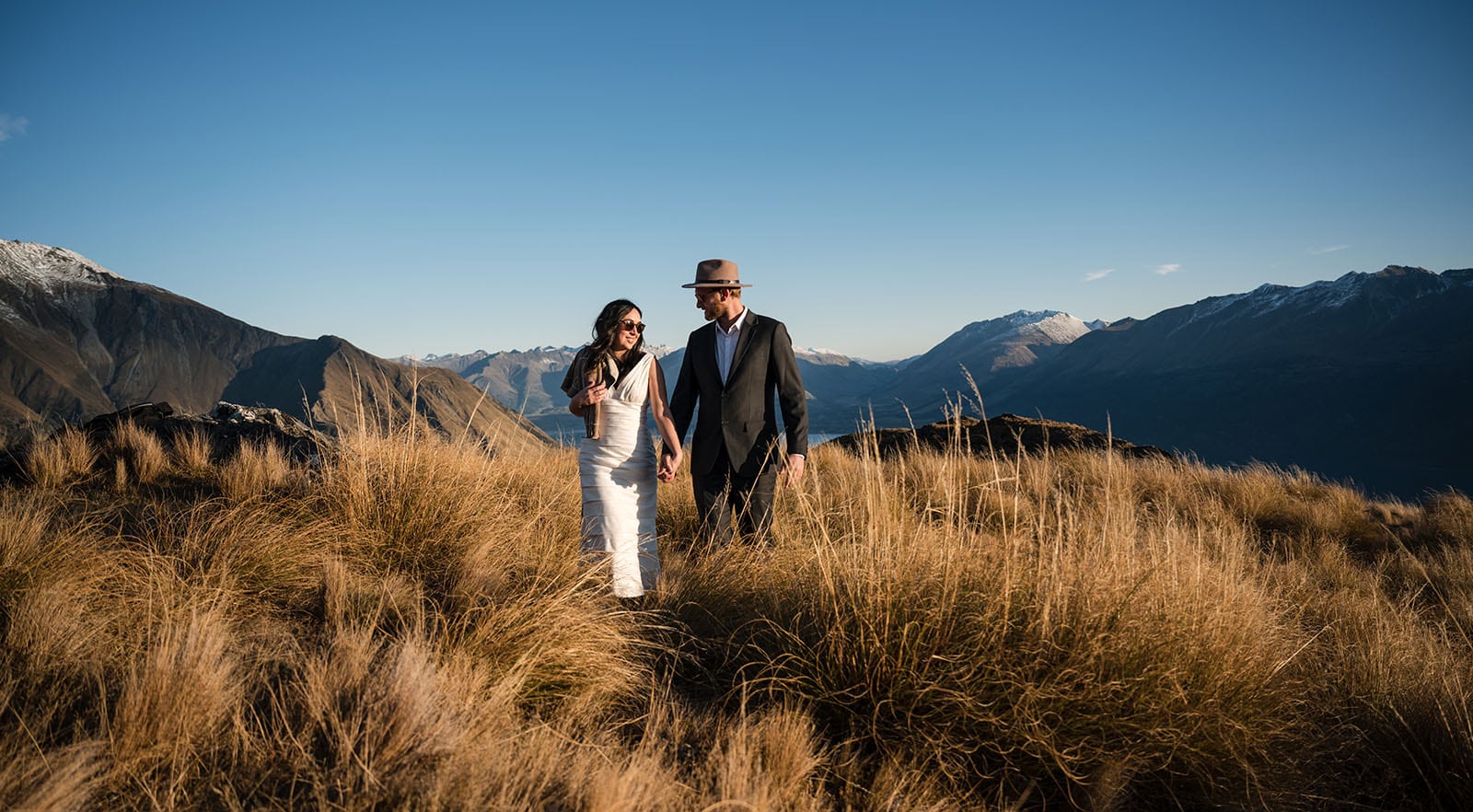 incredible queenstown wedding photoshoot - wendy & frank 45 bride and groom walking through long grass