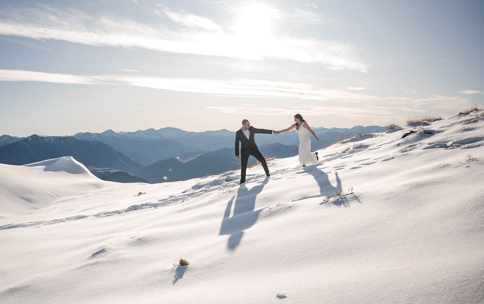 incredible queenstown wedding photoshoot - wendy & frank 25 Bride catching her grooms hand int he snow