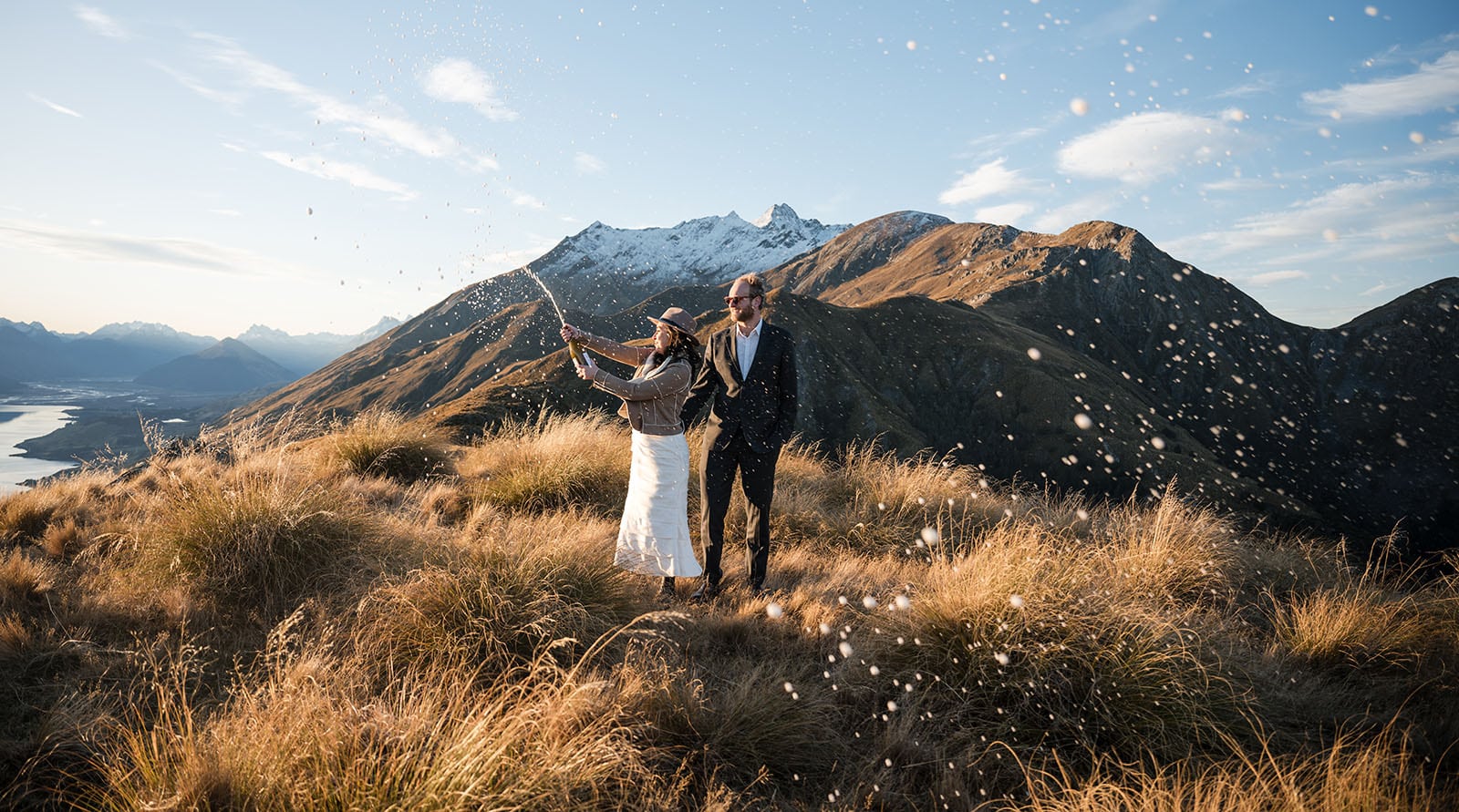 incredible queenstown wedding photoshoot - wendy & frank 52 bride spraying champagne on mountain top