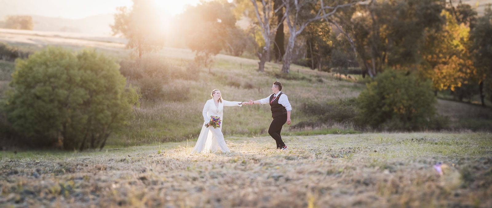 tiny house on the prairie wedding - kat & stacey 110 Bridal couple dragging each other through field