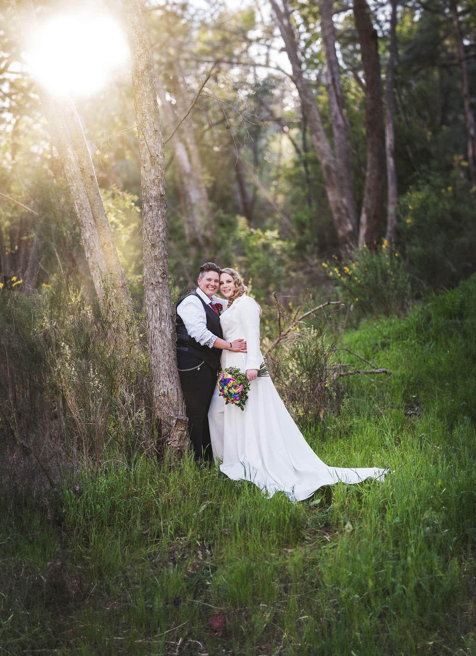 tiny house on the prairie wedding - kat & stacey 97 bridal couple leaning on tree under sun