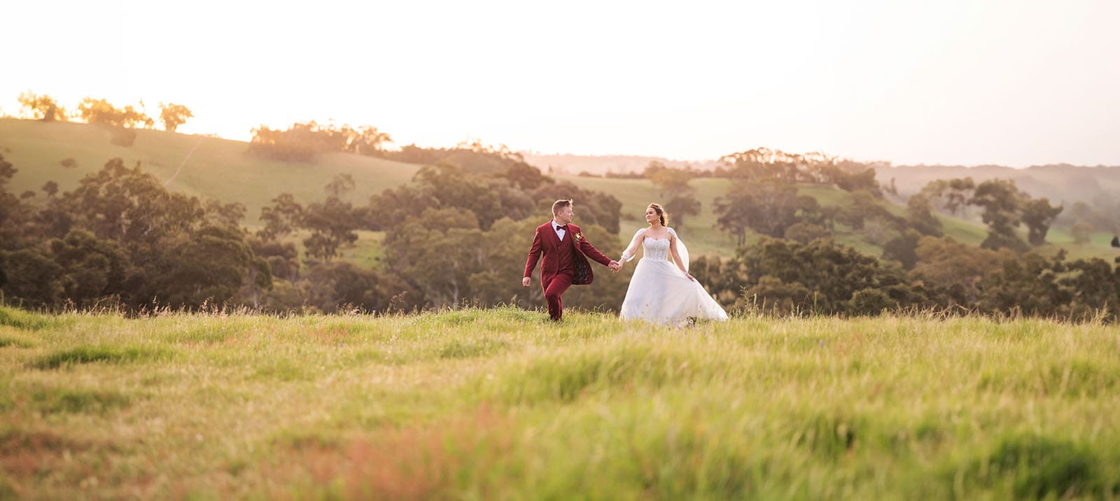 templewood house wedding - michelle & andrew 39 Bride and groom walking in grass at sunset