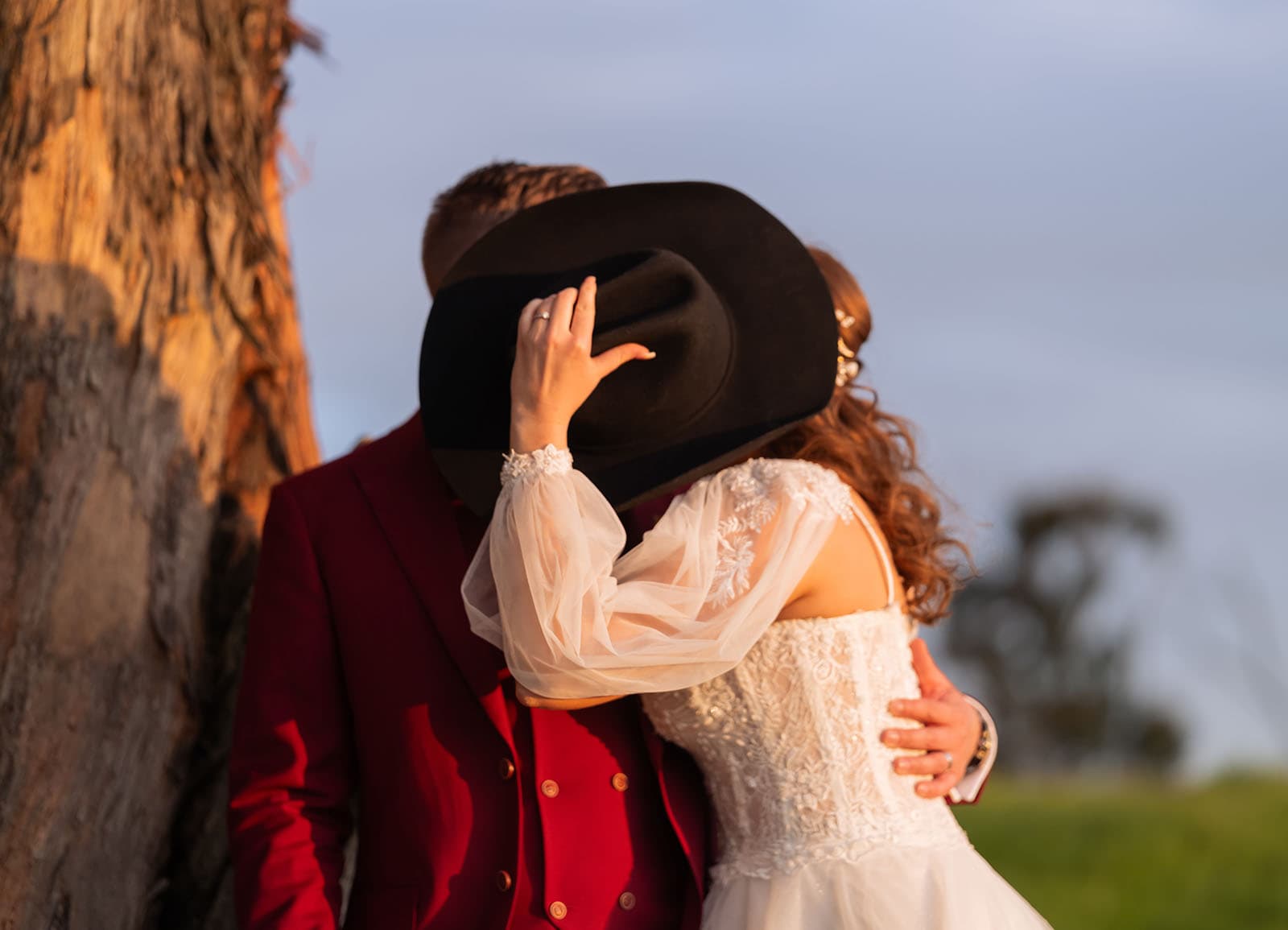 templewood house wedding - michelle & andrew 36 Bride and groom kiss behind hat