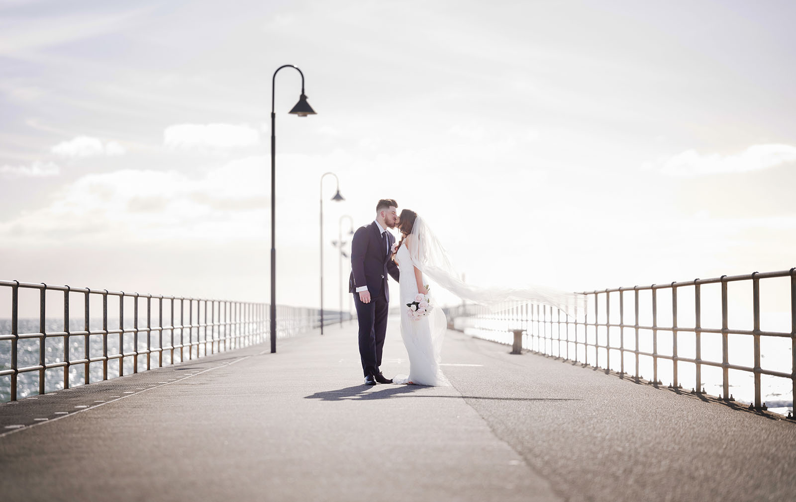 stamford grand wedding - jess & tim 76 bride and groom kiss on Glenelg Jetty