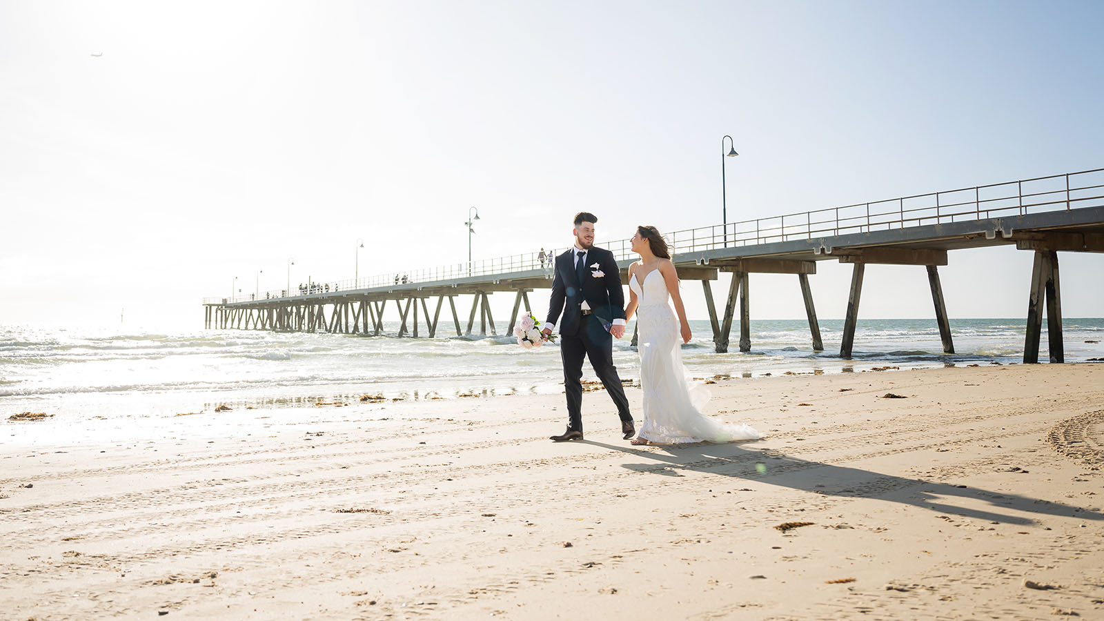 stamford grand wedding - jess & tim 80 Bride and groom walking along Glenelg Beach