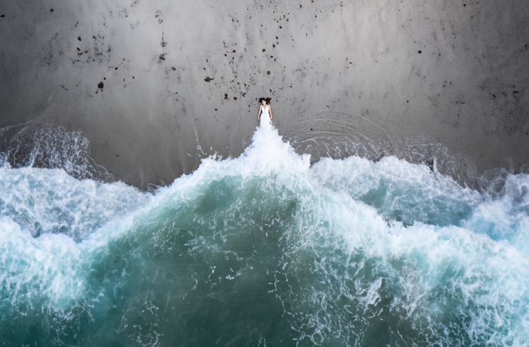 Bride laying on beach with waves