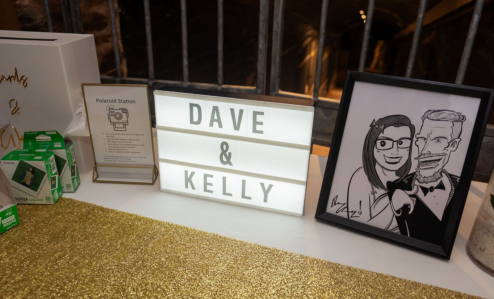 botanic gardens palm house wedding - kelly & david 125 Illuminated Dave and Kelly sign beside a Polaroid station notice, instant film packs and framed caricature at their wedding
