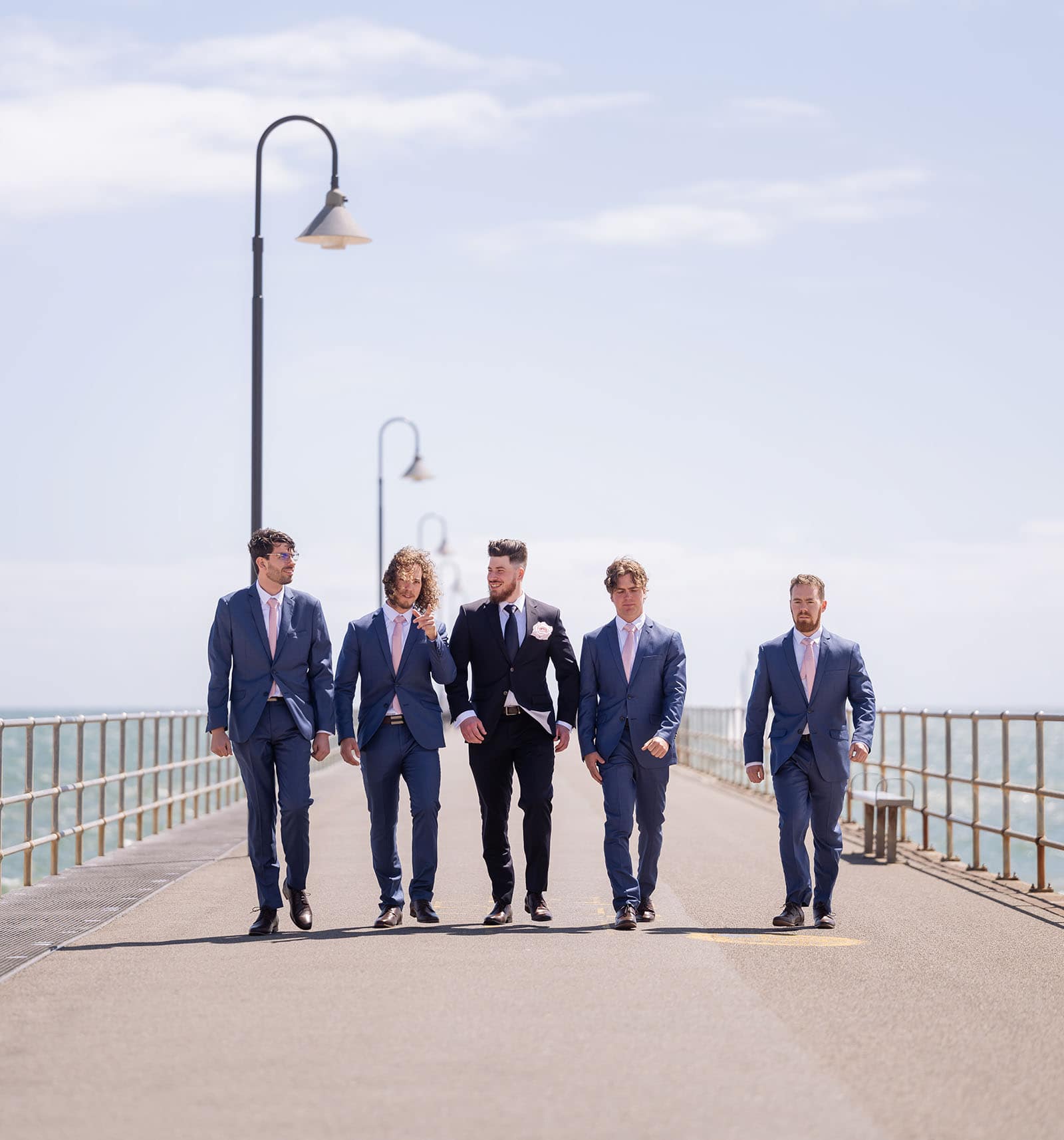 stamford grand wedding - jess & tim 50 Groomsmen walking along Glenelg jetty