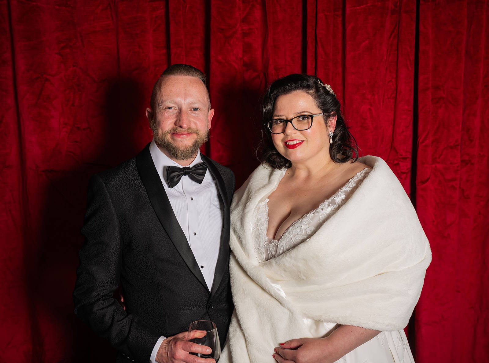 botanic gardens palm house wedding - kelly & david 127 Kelly and David in wedding attire posing before a red velvet curtain, with David holding a wine glass
