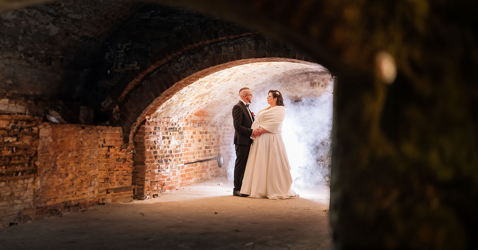 botanic gardens palm house wedding - kelly & david 120 Bride and groom holding hands beneath a brick archway in the Lion Hotel cellars