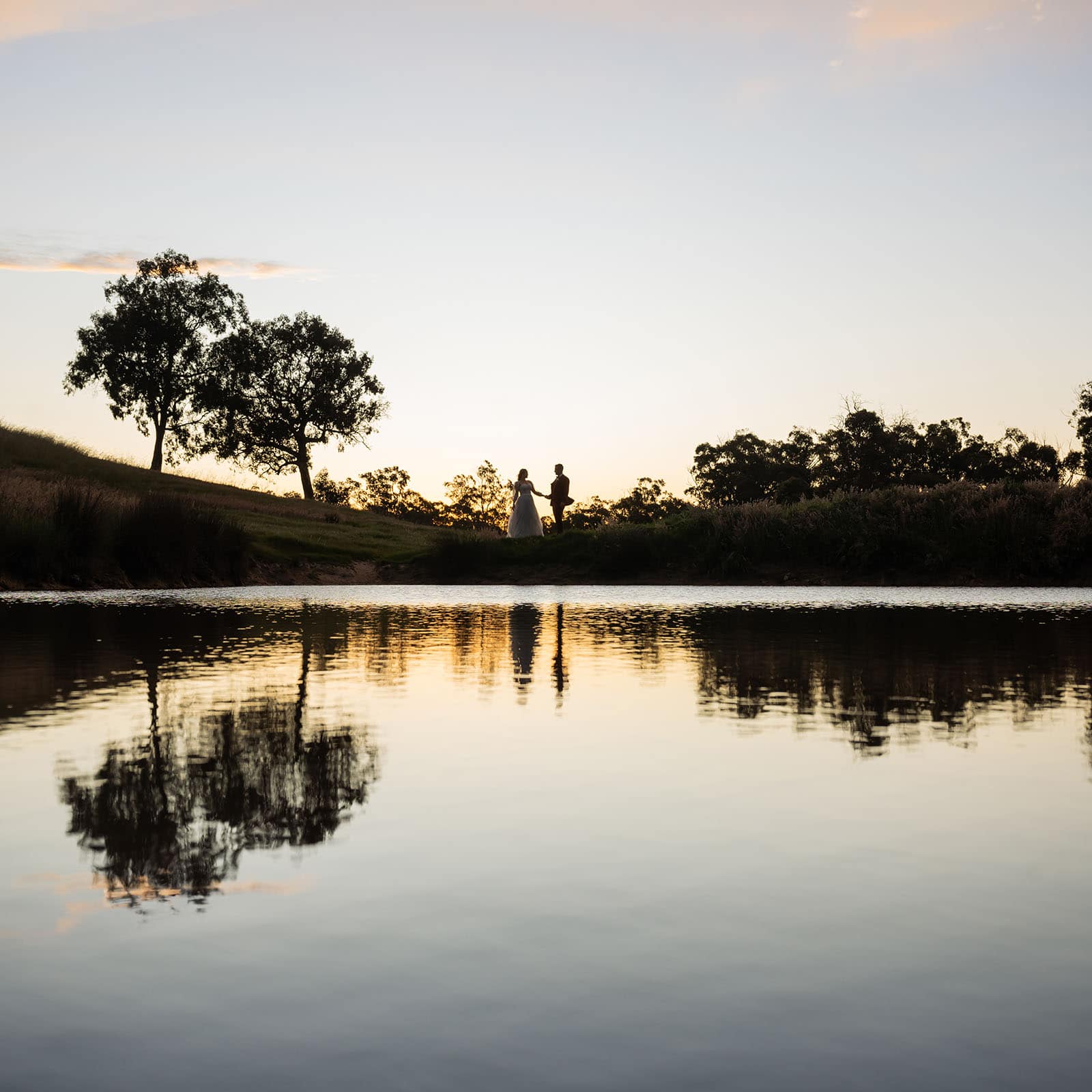 templewood house wedding - michelle & andrew 42 Sillouhette of couple on edge of pond