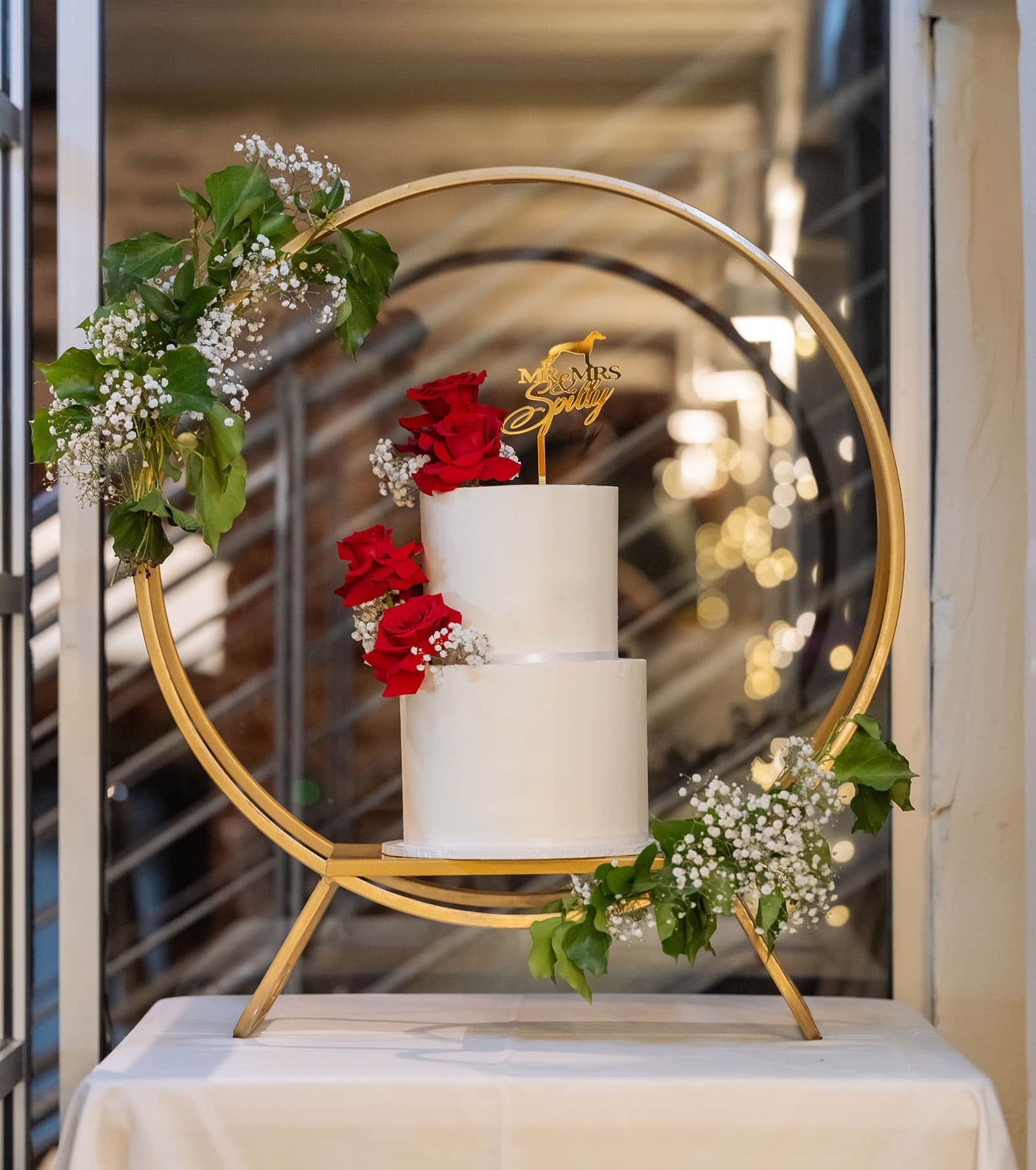 botanic gardens palm house wedding - kelly & david 122 Two-tier white wedding cake decorated with red roses and baby's breath on a gold circular stand