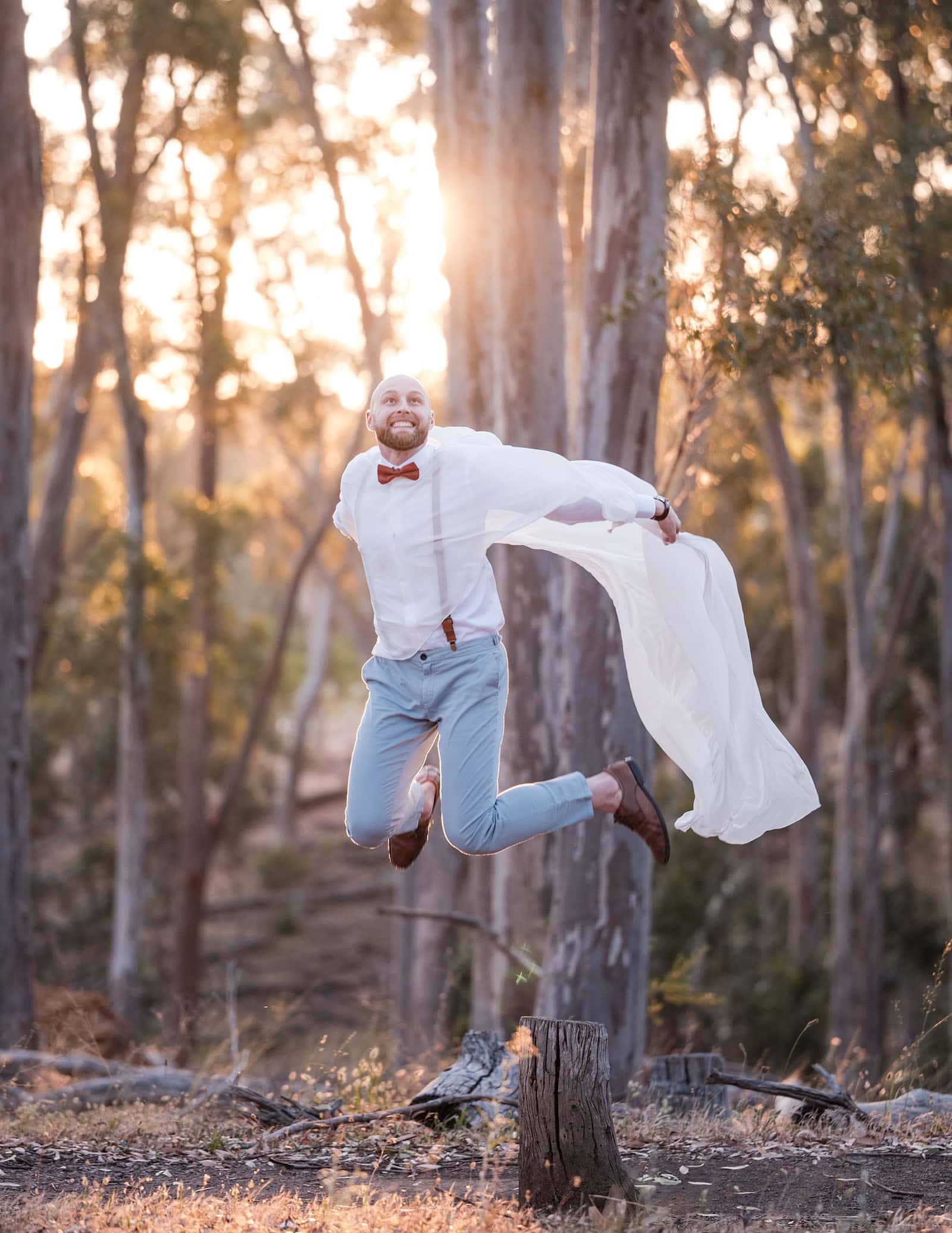 belair national park engagement shoot - lindsey & jaden 37 Man jumping joyfully in forest at sunset