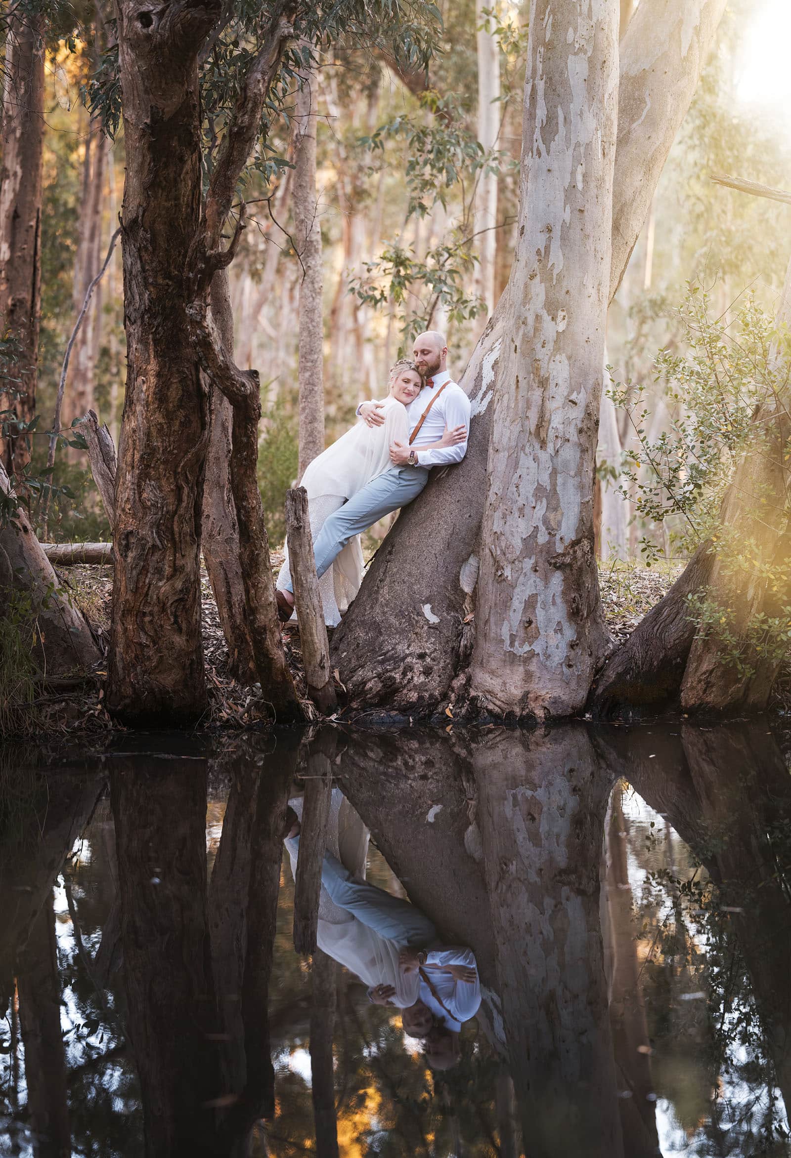 belair national park engagement shoot - lindsey & jaden 32 Couple embracing on tree trunk with reflection in water