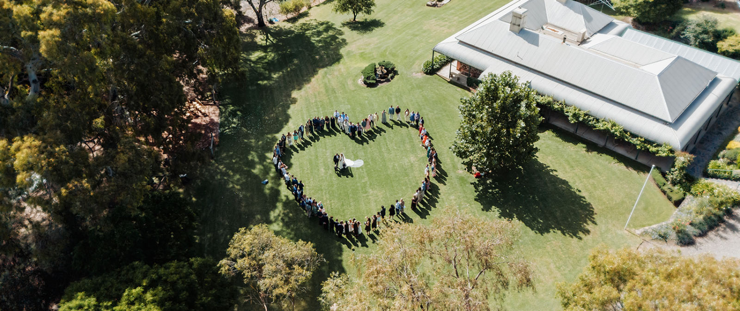outdoor wedding ceremony aerial view with guests forming heart shape