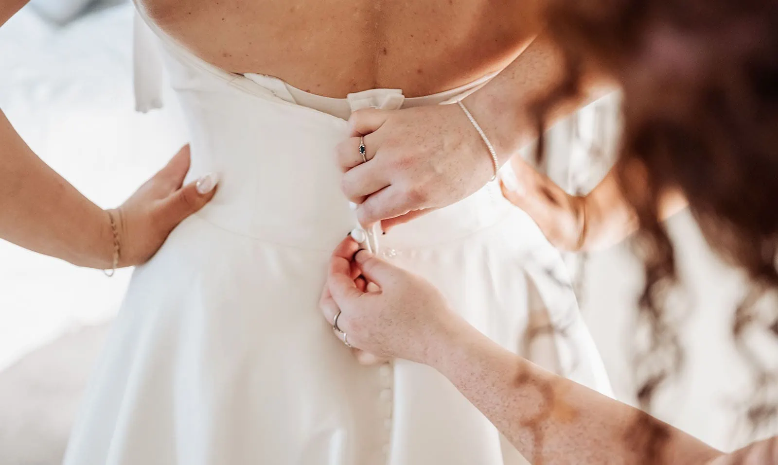 botanic gardens, araucaria avenue wedding - jade & hazim 18 Assistant fastening fabric buttons on brides elegant white wedding gown.