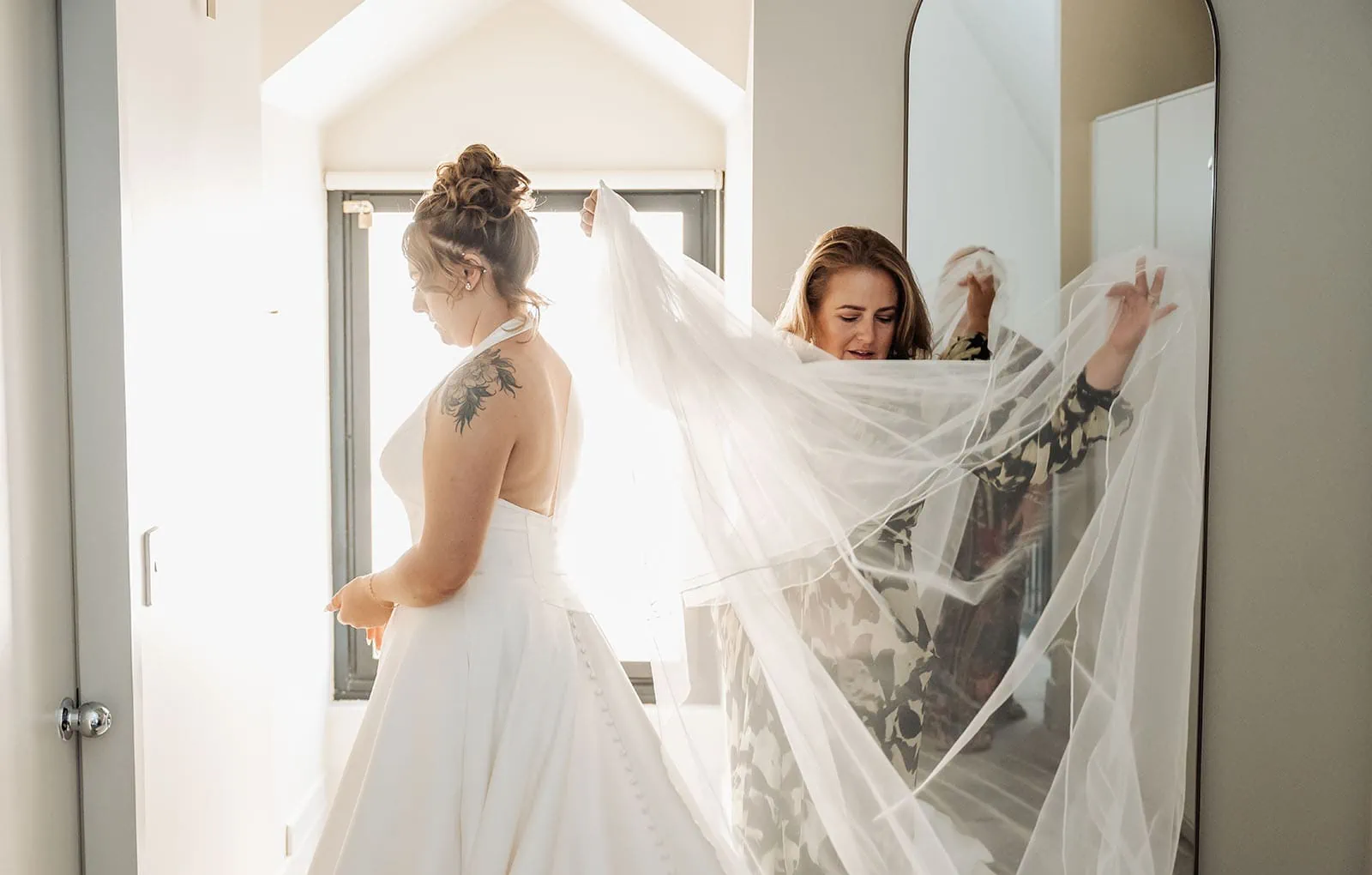botanic gardens, araucaria avenue wedding - jade & hazim 20 Bride in elegant halter dress preparing for wedding with attendants help.