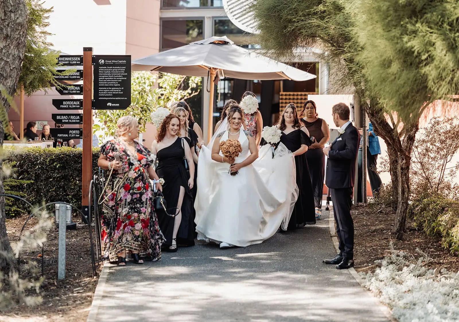 botanic gardens, araucaria avenue wedding - jade & hazim 29 Bride in white gown with attendants at an outdoor wedding celebration.