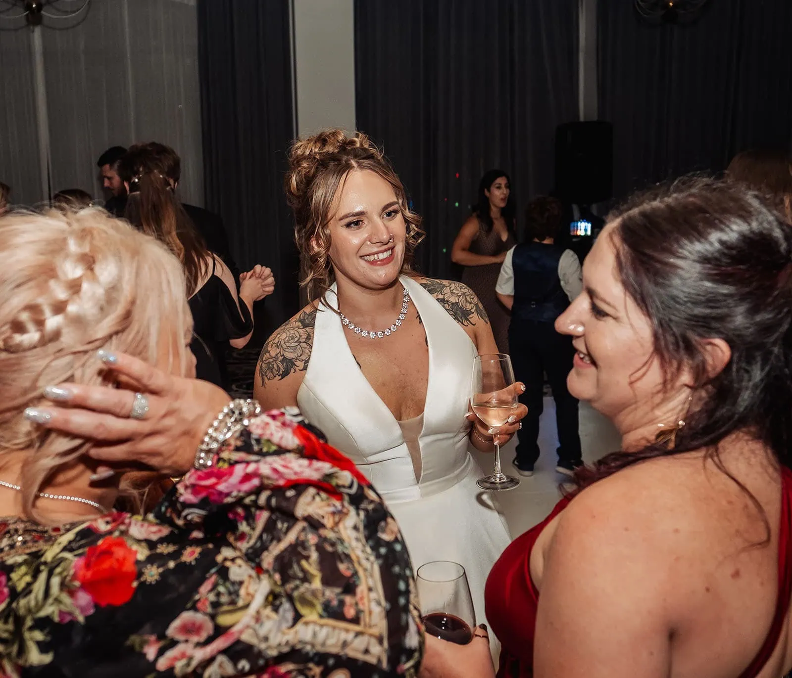 botanic gardens, araucaria avenue wedding - jade & hazim 74 Bride in white dress joyfully conversing with guests at elegant wedding reception.