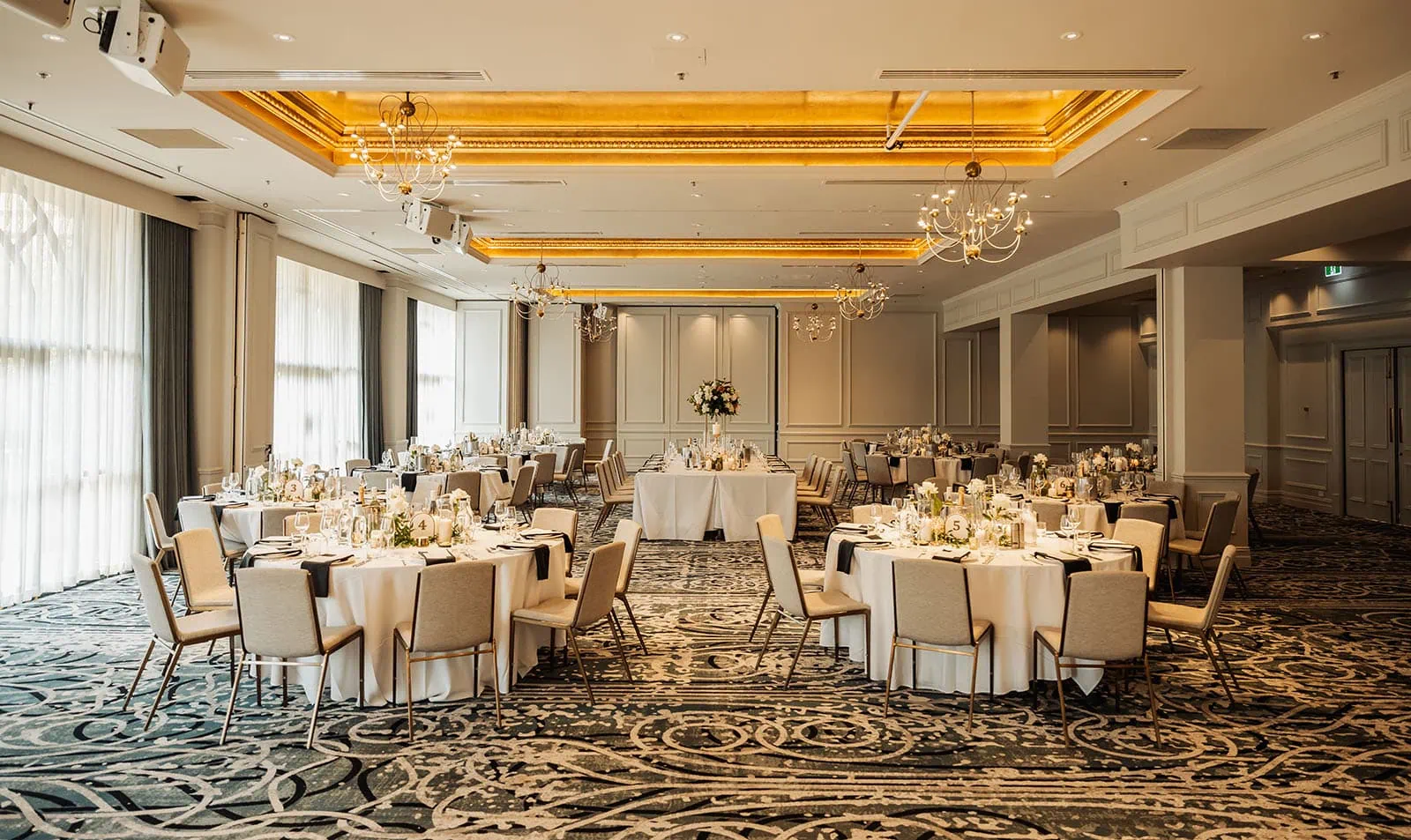 botanic gardens, araucaria avenue wedding - jade & hazim 61 Luxuriously appointed banquet hall with meticulously set tables ready for a formal event.