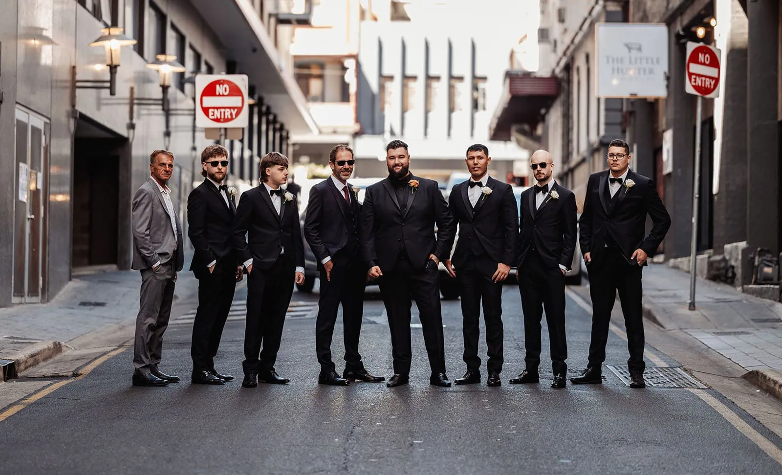 botanic gardens, araucaria avenue wedding - jade & hazim 8 Groom and groomsmen in black suits on urban street for wedding celebration.