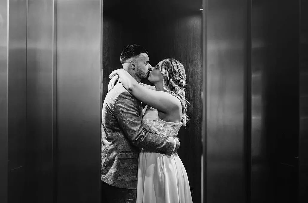 recent wedding featured in the sundaymail 9 Couple sharing intimate kiss in stylish elevator setting.