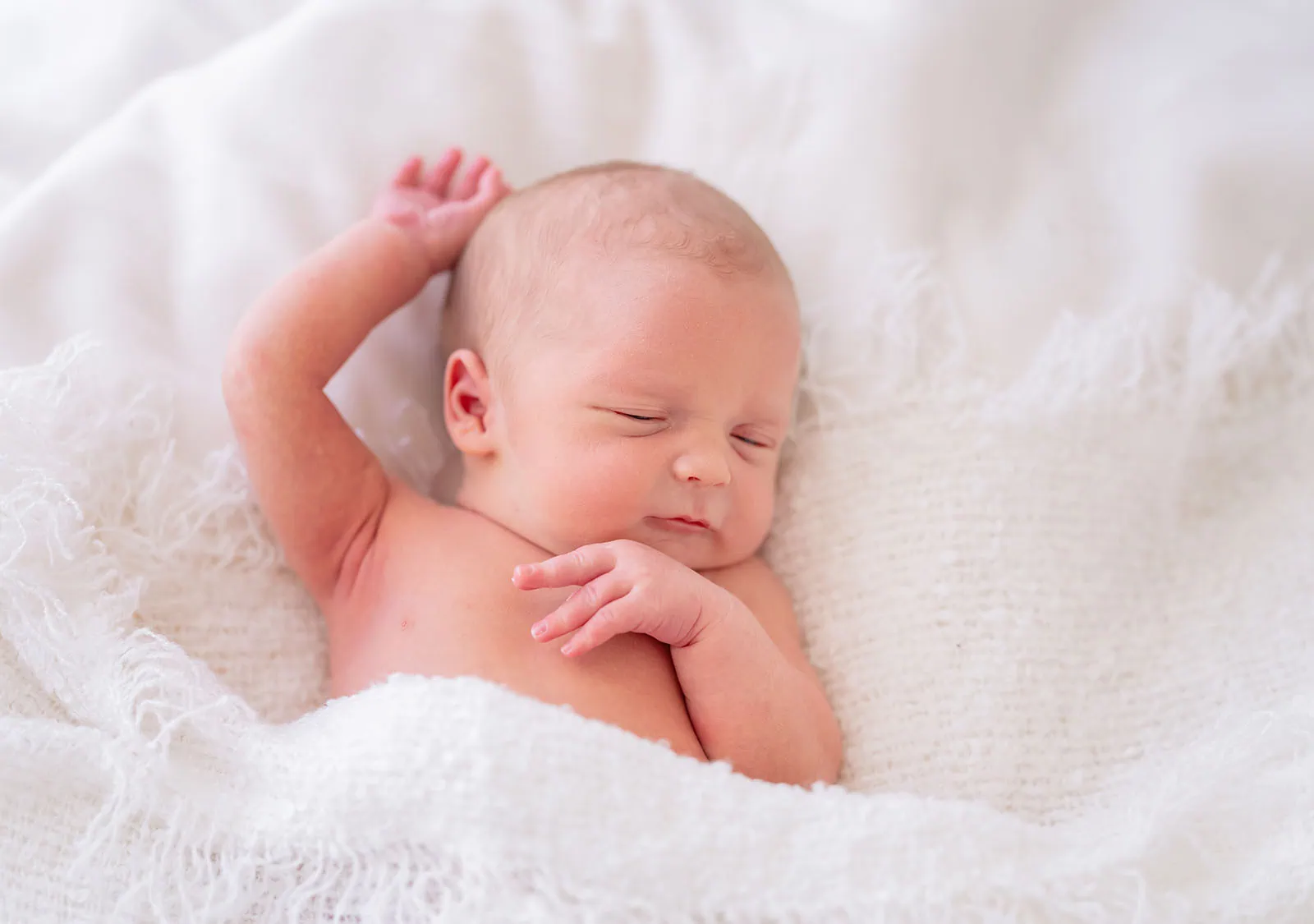 baby spencer's newborn shoot 72 Peaceful newborn baby sleeping on a soft white blanket with a serene expression.