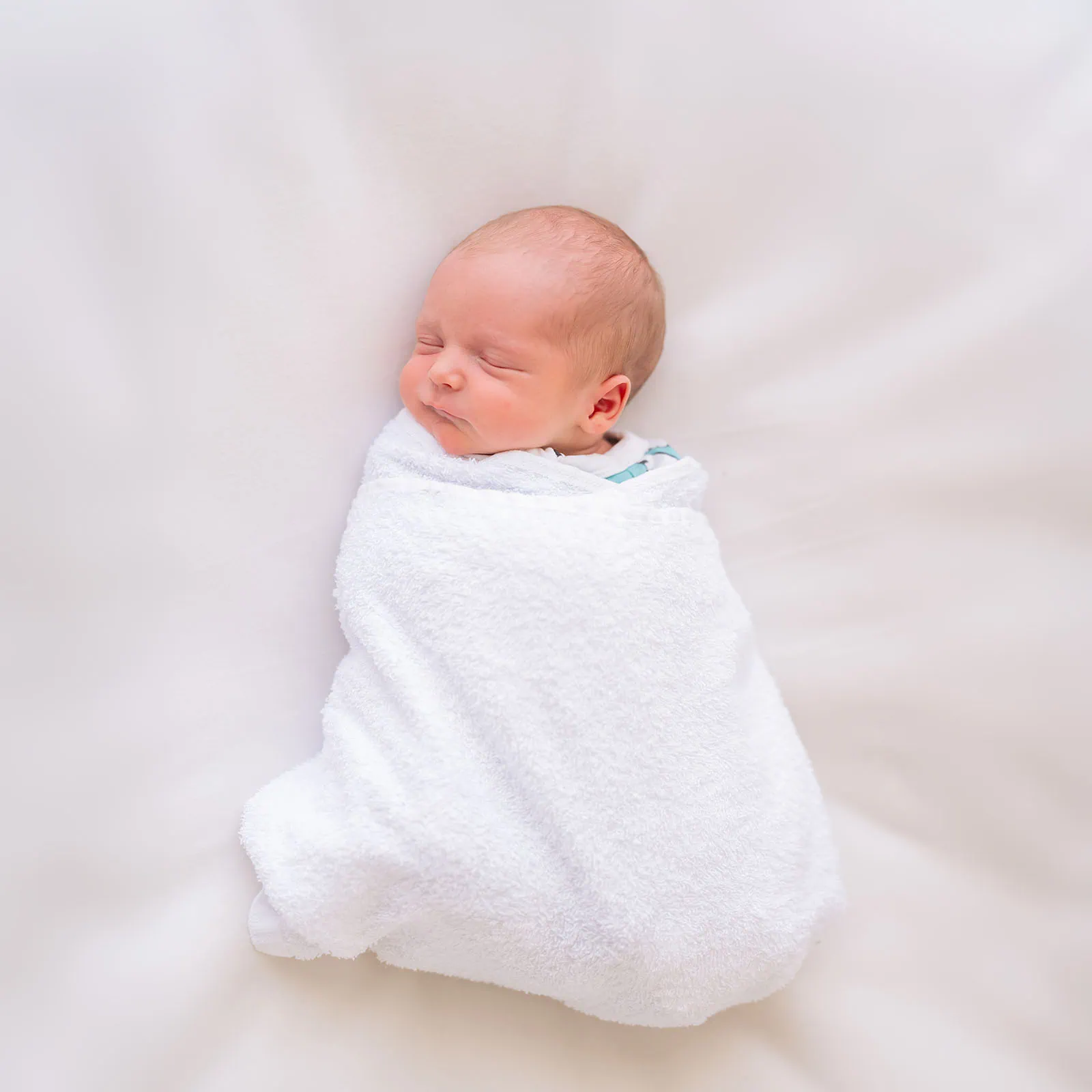 baby spencer's newborn shoot 68 Peaceful newborn baby swaddled in white blanket, sleeping soundly.
