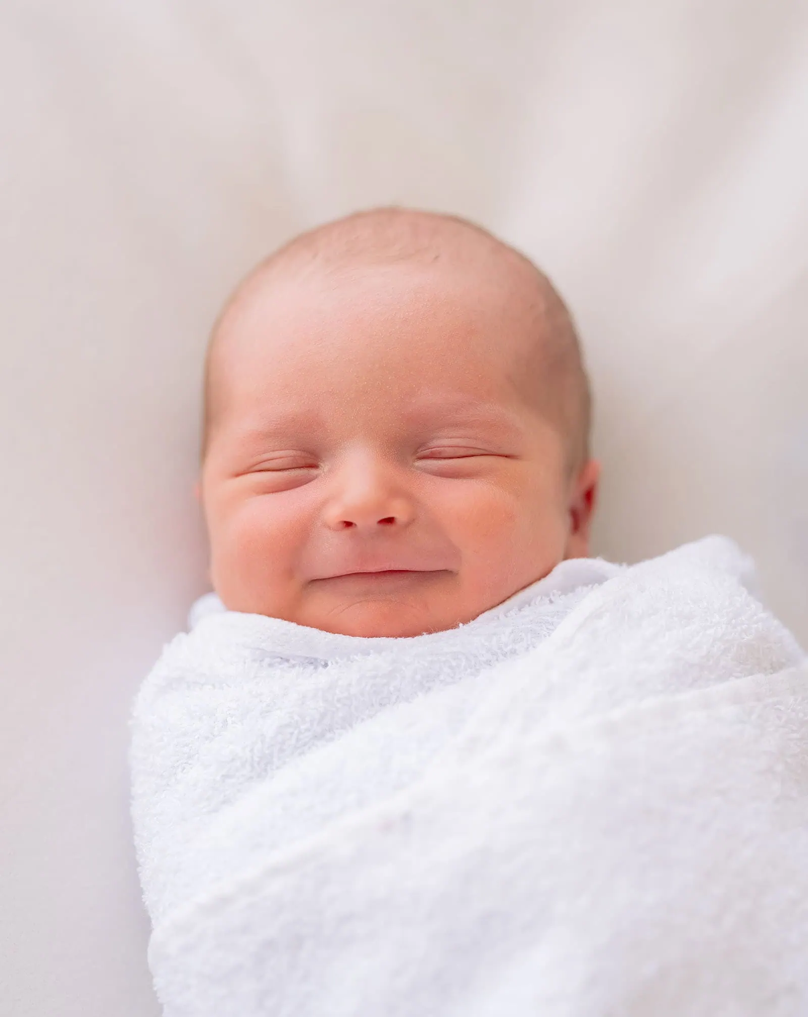 baby spencer's newborn shoot 70 Peaceful newborn baby swaddled in soft white blanket, sleeping.